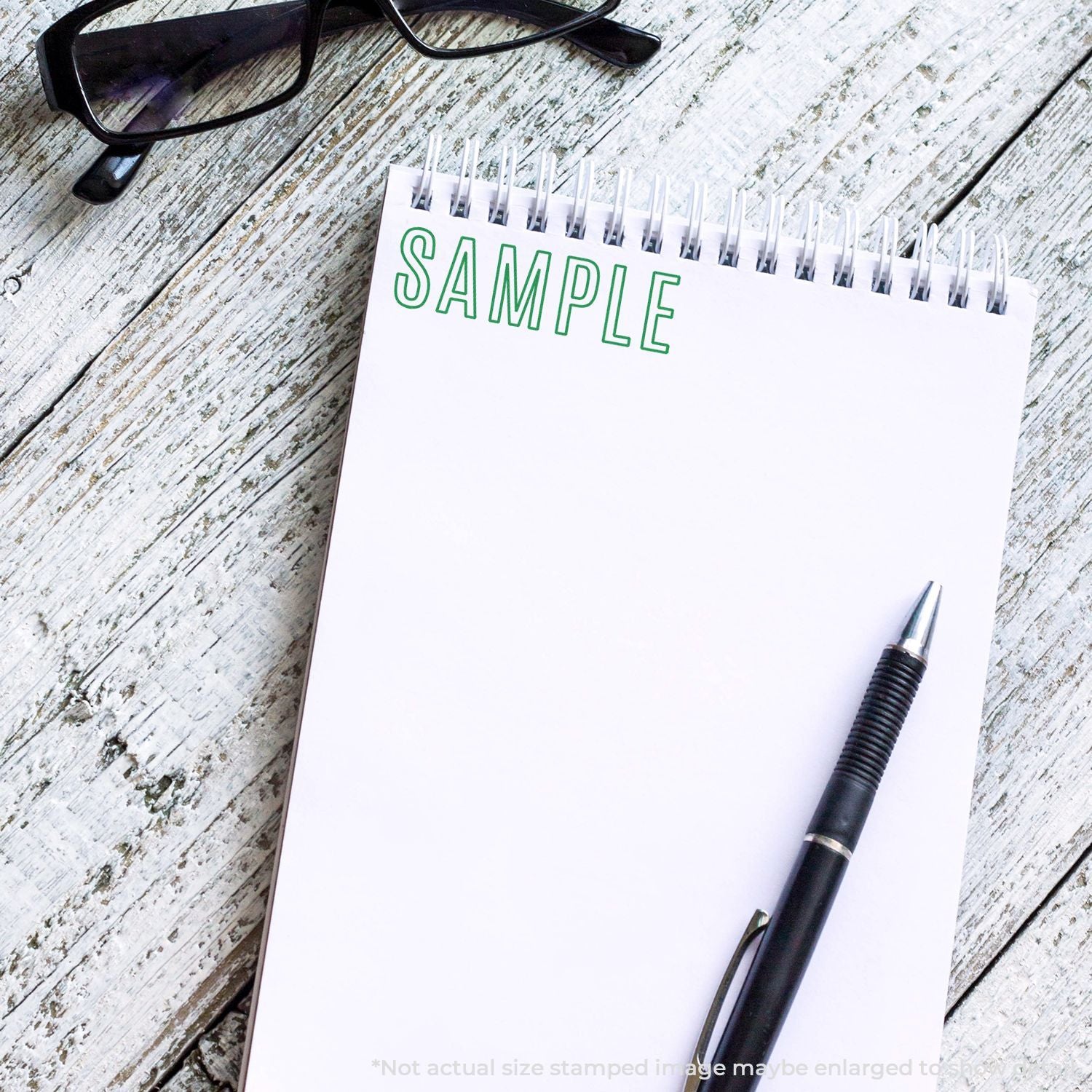 Sample concept: open notebook labeled SAMPLE with green text, pen and eyeglasses on weathered wooden desk for product testing notes.