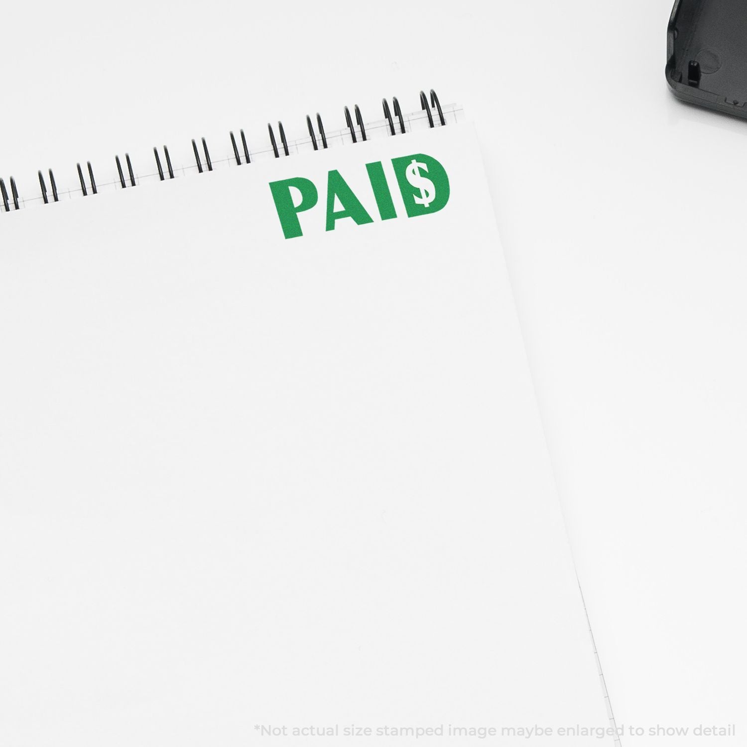White spiral notebook with green PAID stamp, business finance and payment concept.