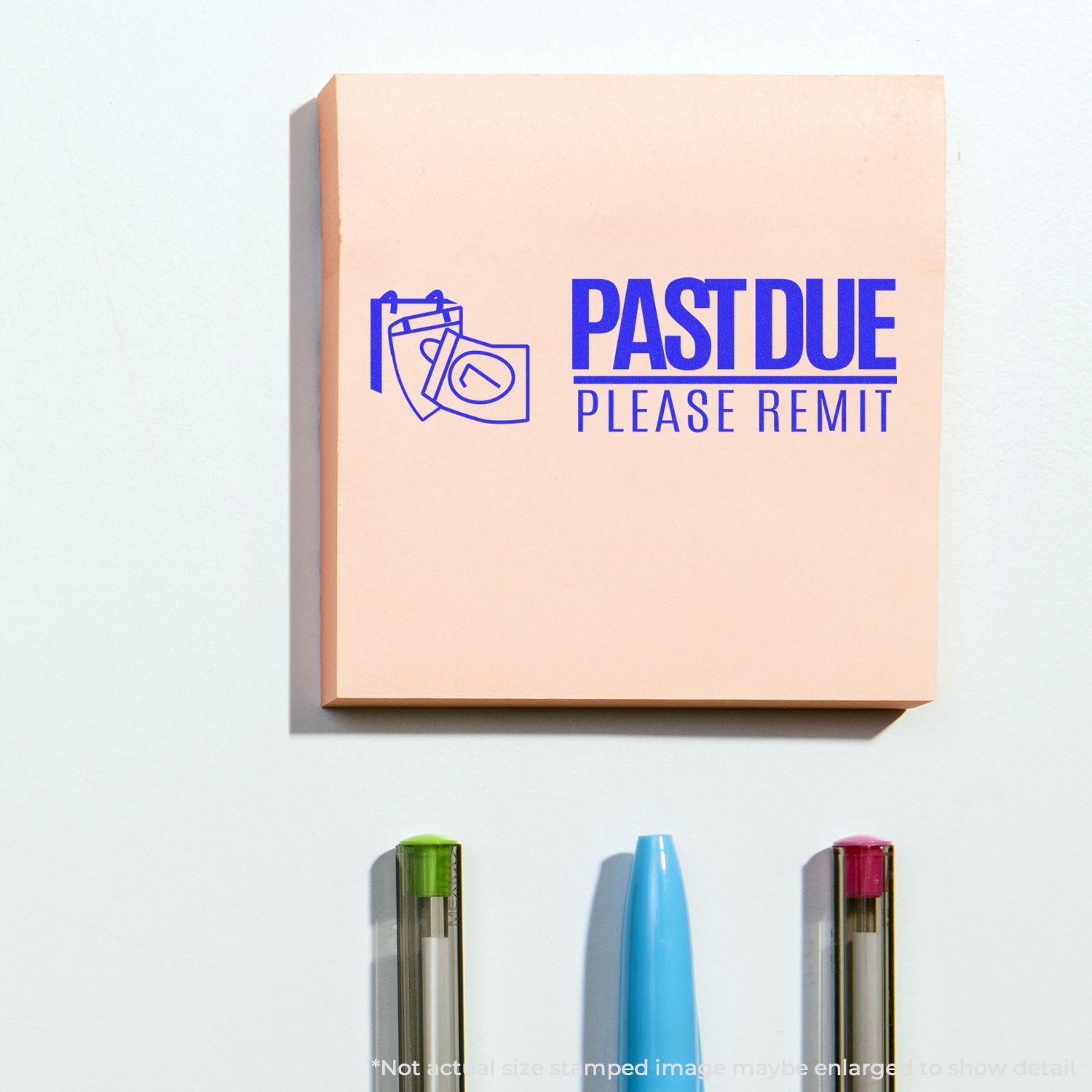 Past due please remit office sign with blue text on a peach background, displayed above pens on a white wall.