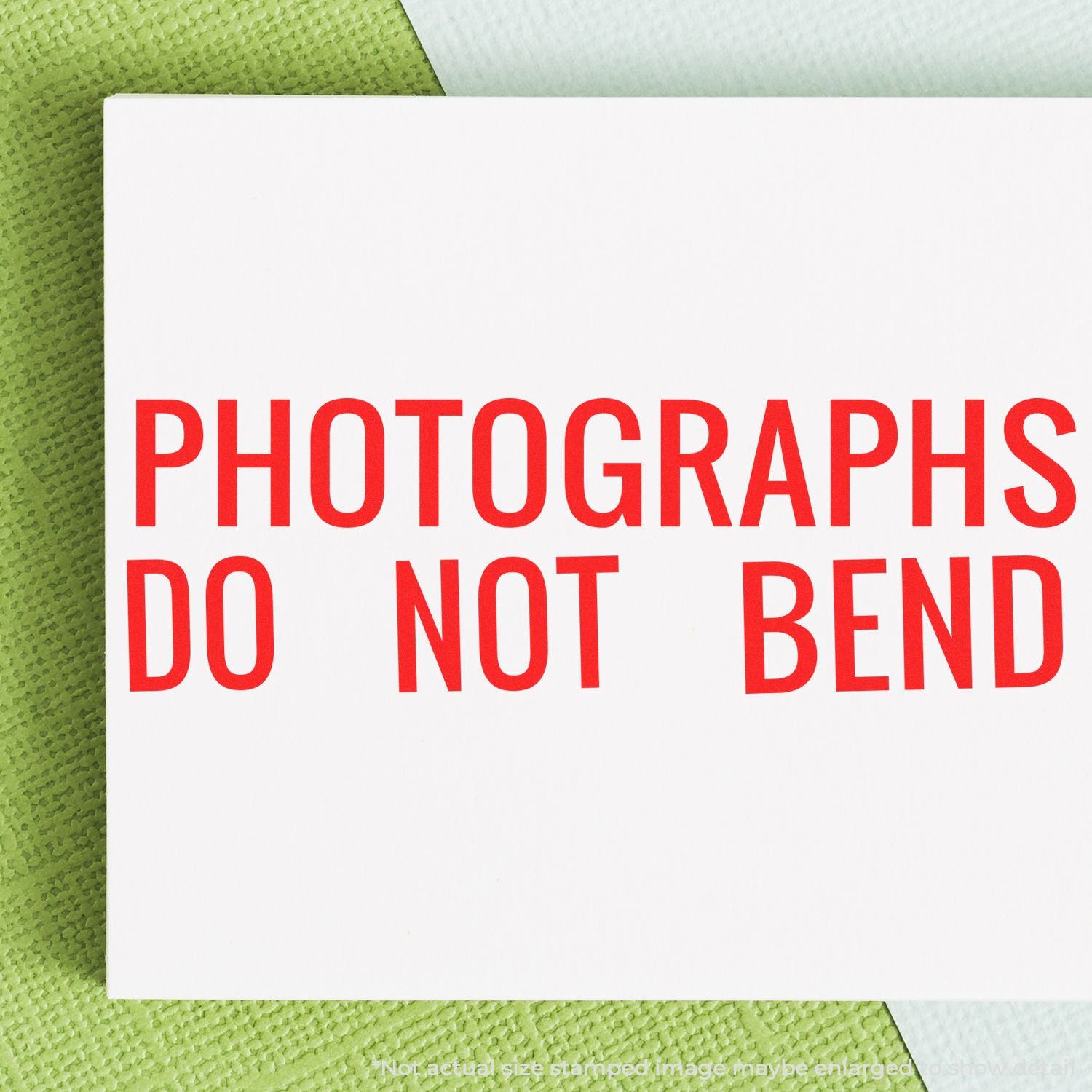 Photo preservation warning card reading PHOTOGRAPHS DO NOT BEND on a green textured surface, for proper handling.