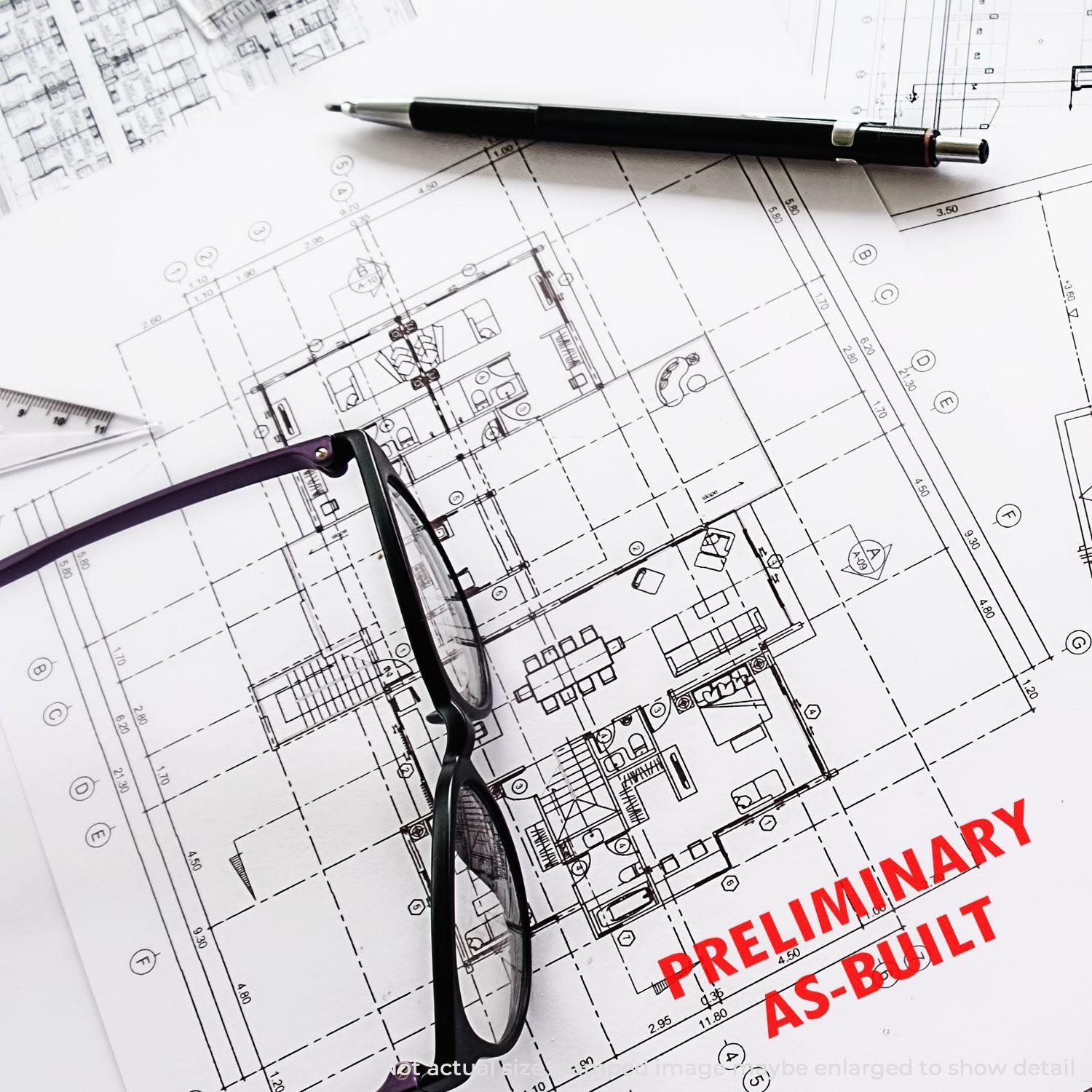 Architectural floor plan blueprint with pen, eyeglasses, and Preliminary As-Built design review document.