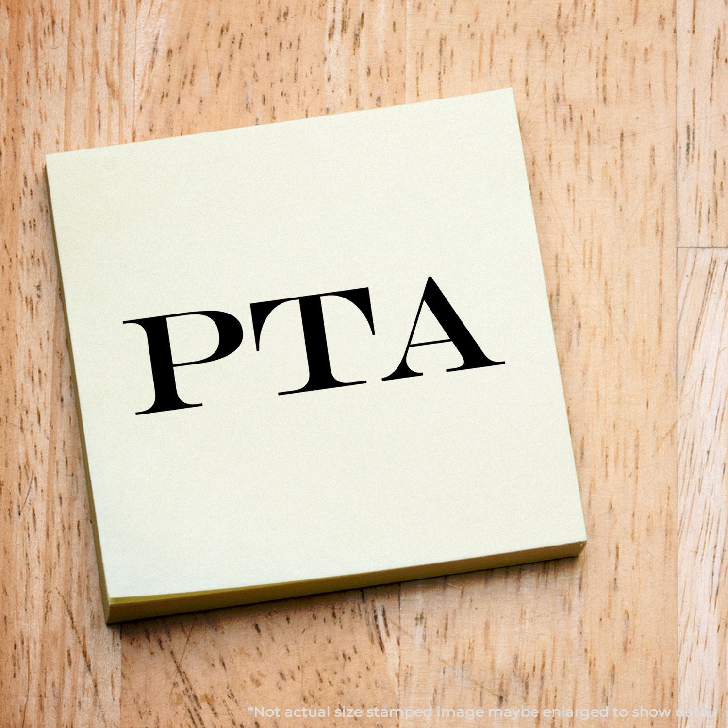 PTA stamp on white paper card against rustic wood surface, showing PTA branding letters for informational materials