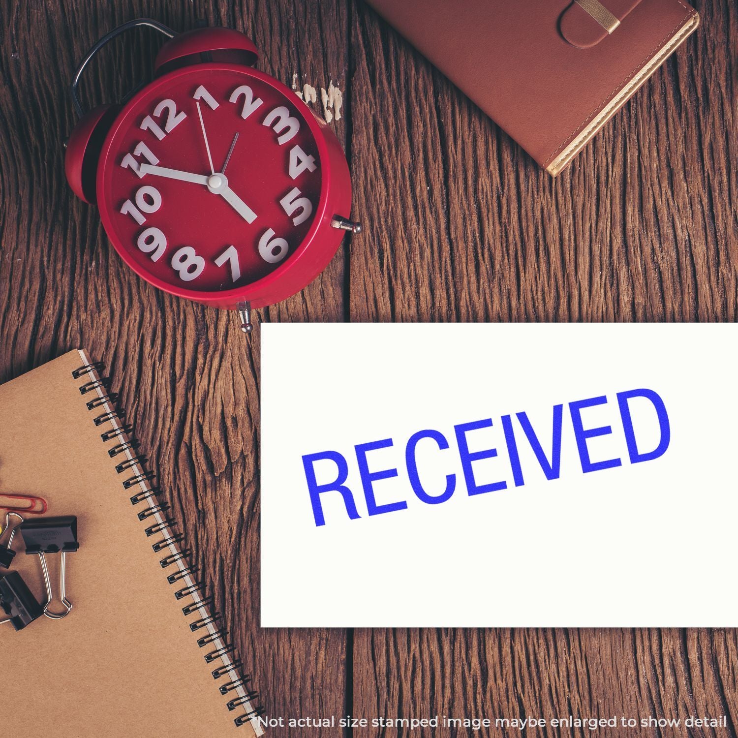 Alarm clock and stationery on wooden desk with RECEIVED sign, illustrating timely receipt and confirmation.