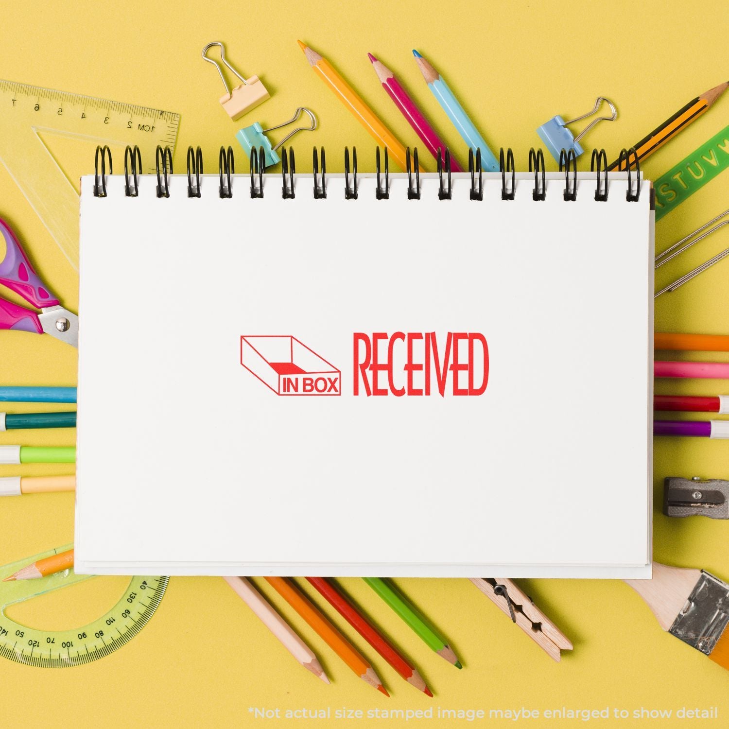 Stationery delivery concept: spiral notebook labeled Received in Box with colored pencils, ruler, and school supplies on yellow.