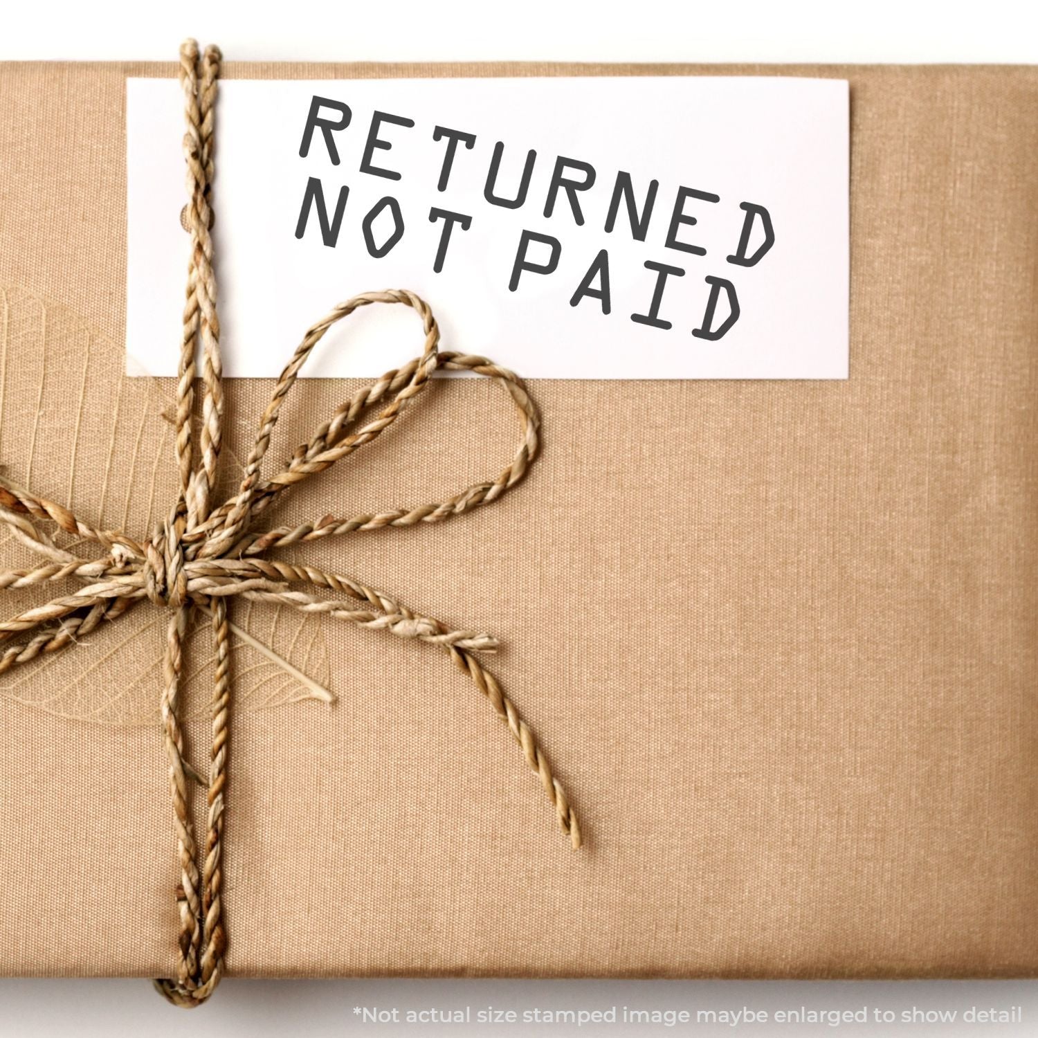 Wrapped kraft paper gift with twine bow and Returned Not Paid tag, close-up of rustic parcel packaging.