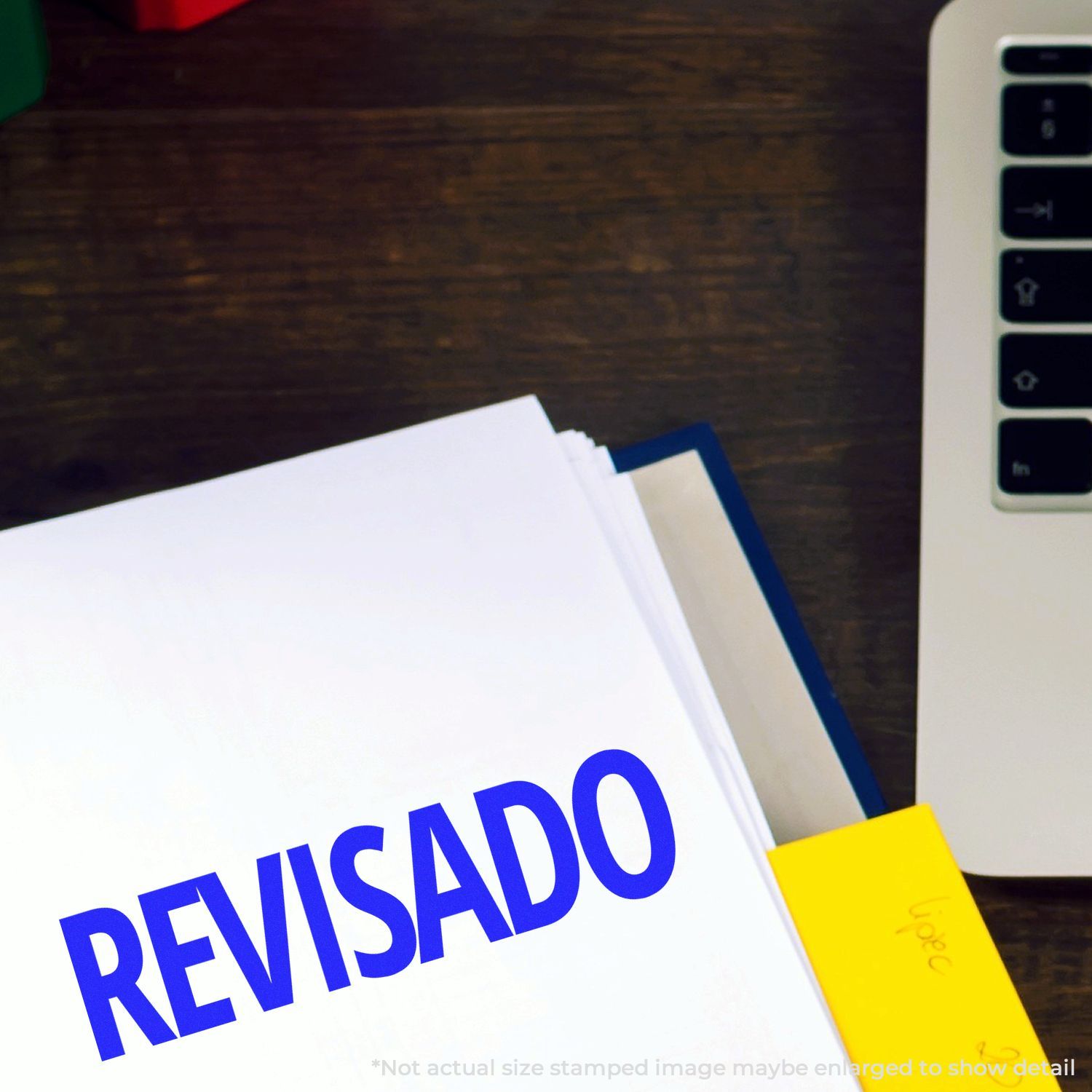 Reviewed documents on an office desk beside a laptop keyboard, with a folder stamped REVISADO.