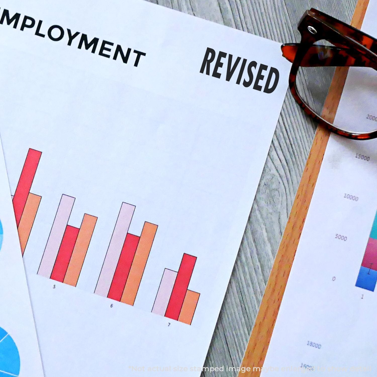 Revised employment report with bar charts and eyeglasses on a desk for business analysis and workforce statistics.