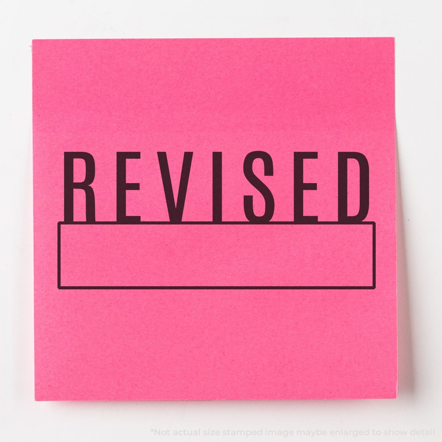 Pink revision stamp reading REVISED on a label card, indicating updated documentation or changes.
