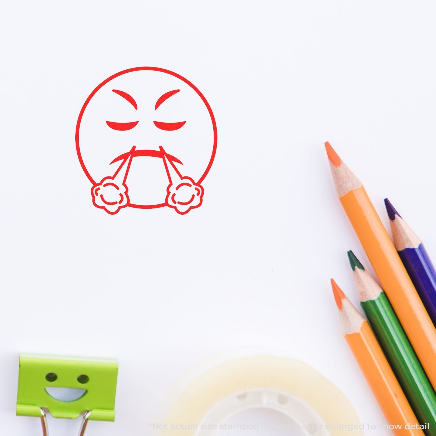 Red angry emoji stamp on white paper with colorful pencils and a smiling binder clip stationery set.