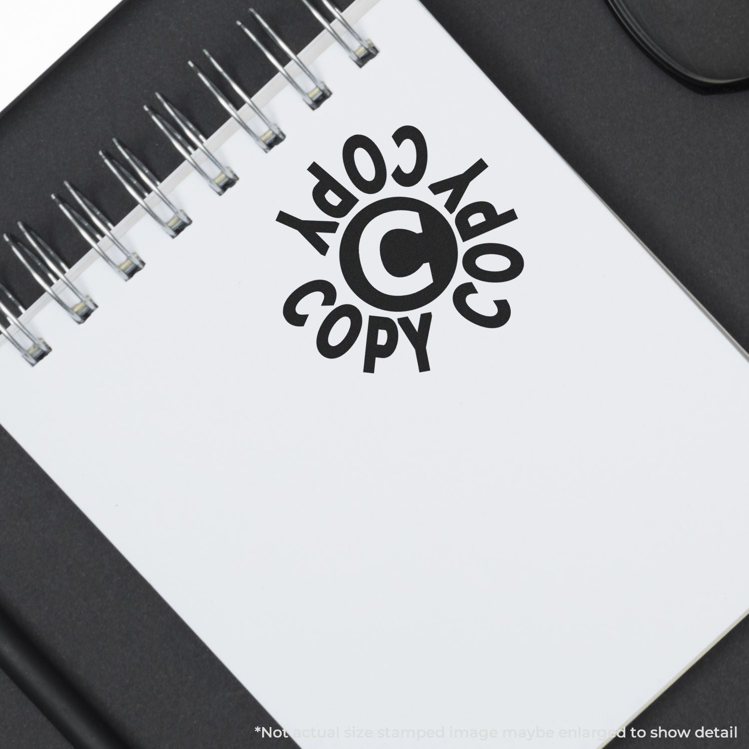 Spiral notebook with copyright symbol logo on white cover, black office stationery background