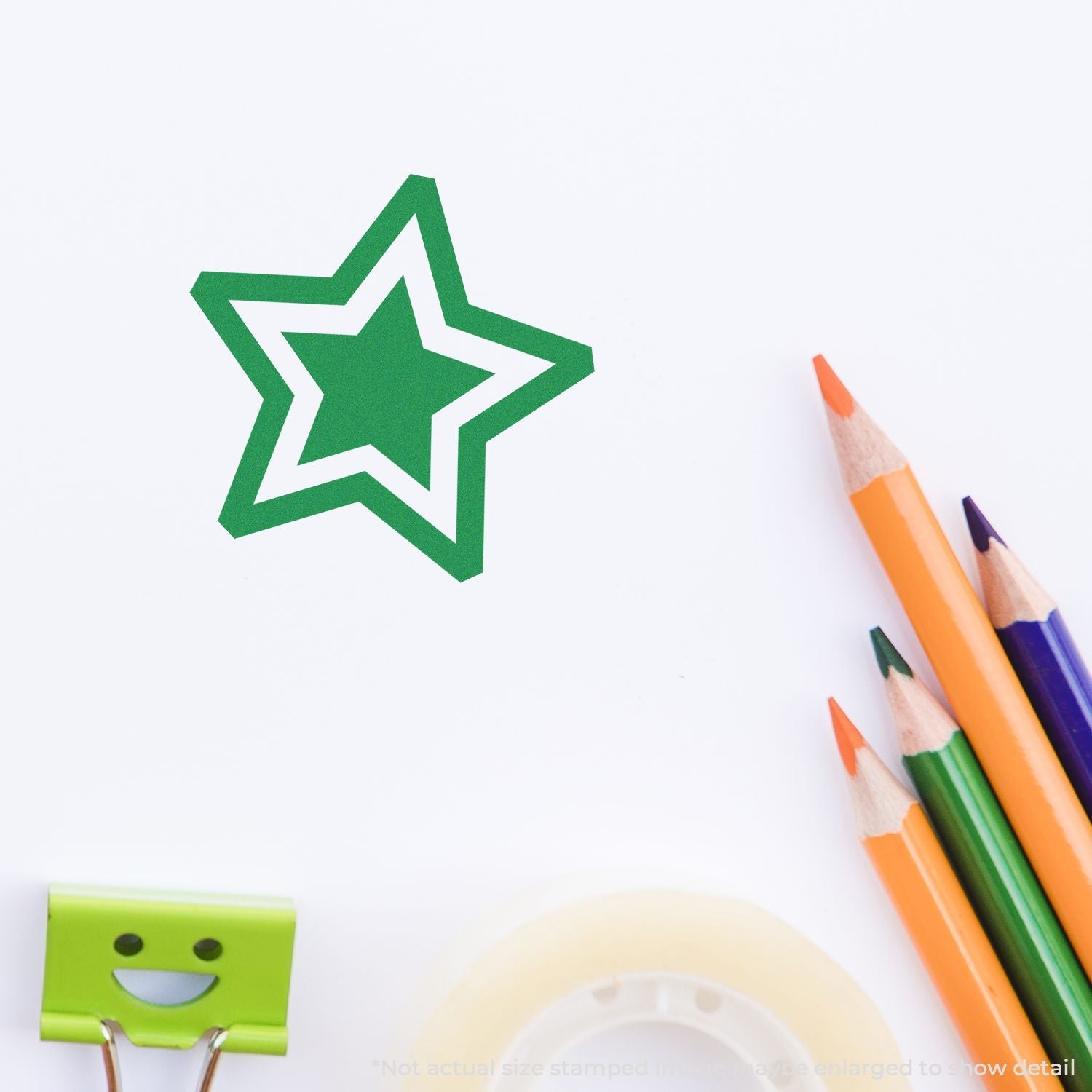Green star paper cutout with colorful pencils and a smiling binder clip on a white background, creative stationery flat lay.