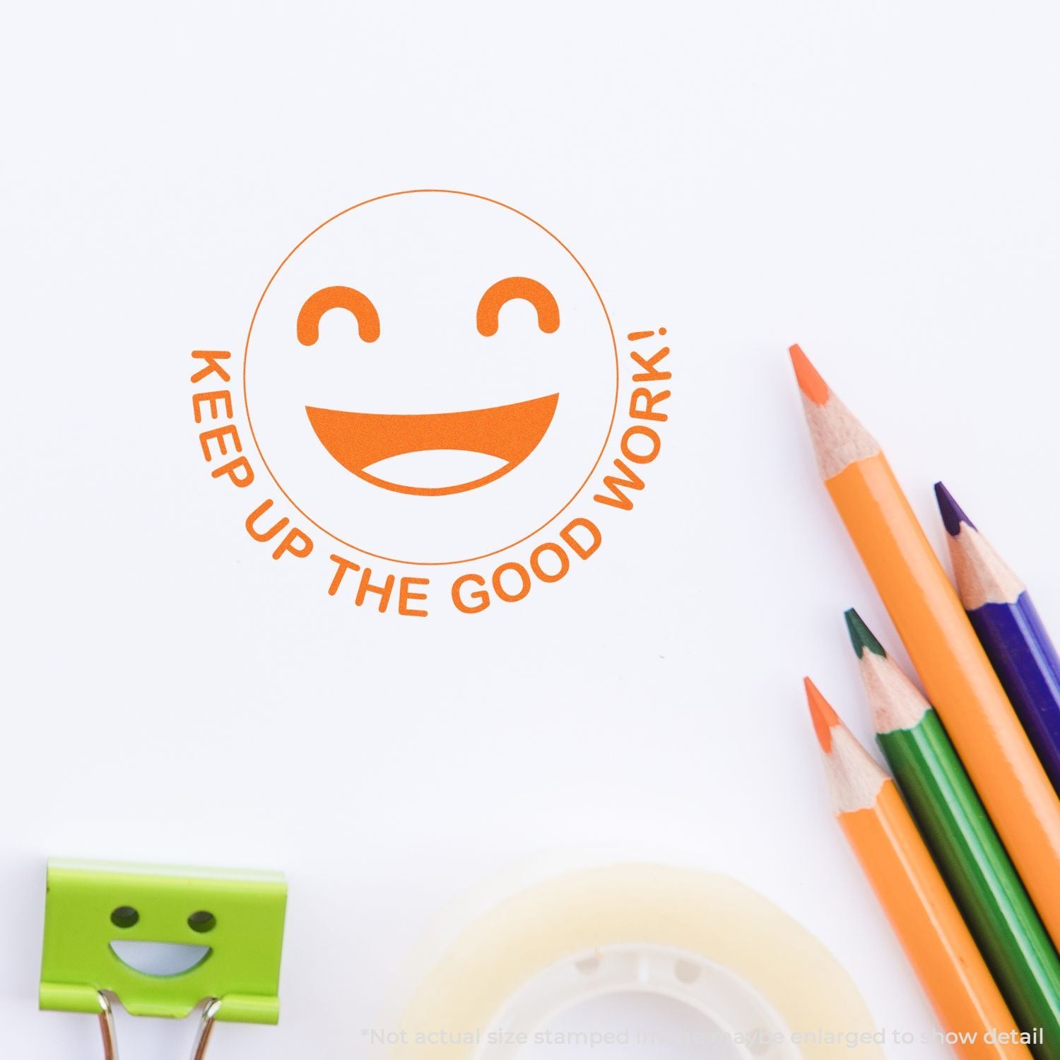 Orange Keep Up the Good Work! smiley stamp with colorful pencils and a green binder clip on white paper