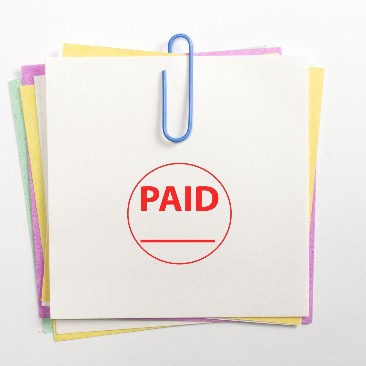 Stack of paper documents clipped together with a red PAID stamp, invoice payment confirmation concept