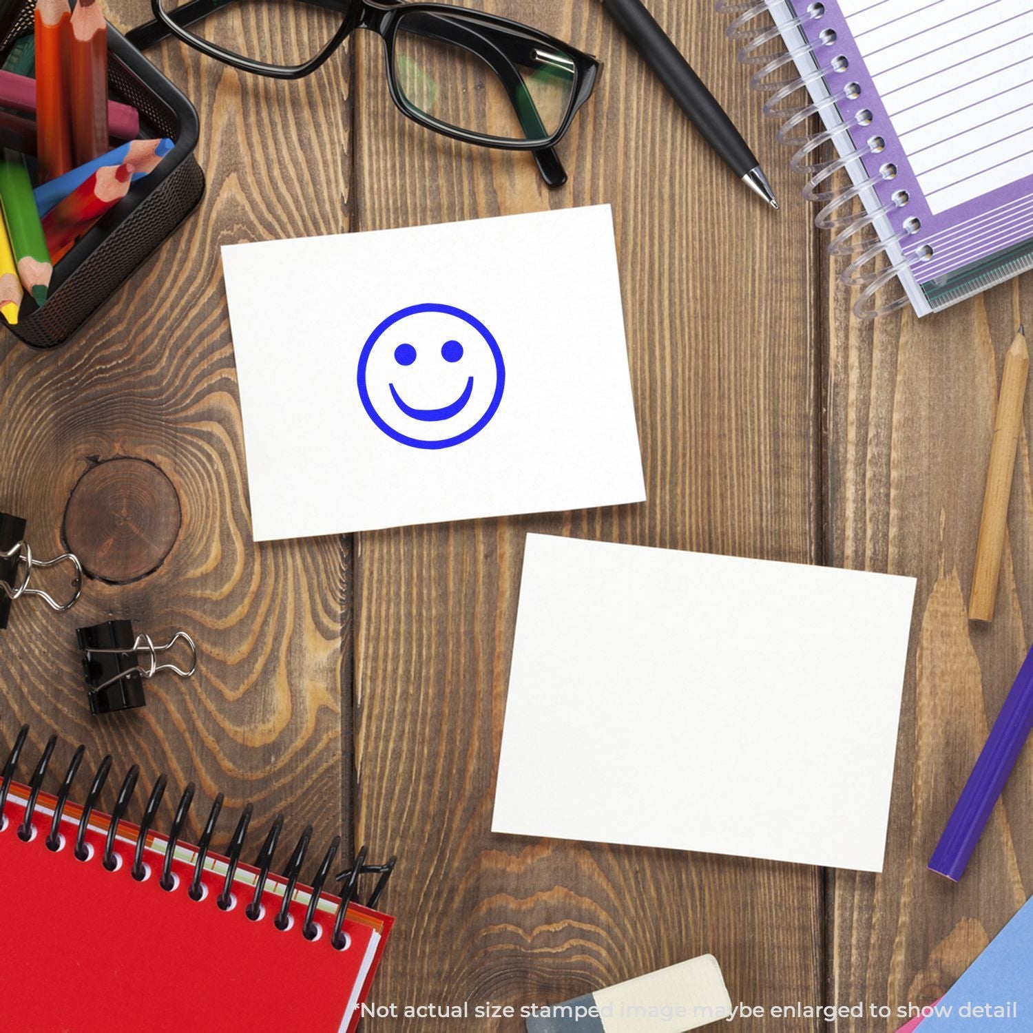 Smiley face sticky note on wooden desk with stationery, notebook, glasses, and pencils for office planning and creative workspace.