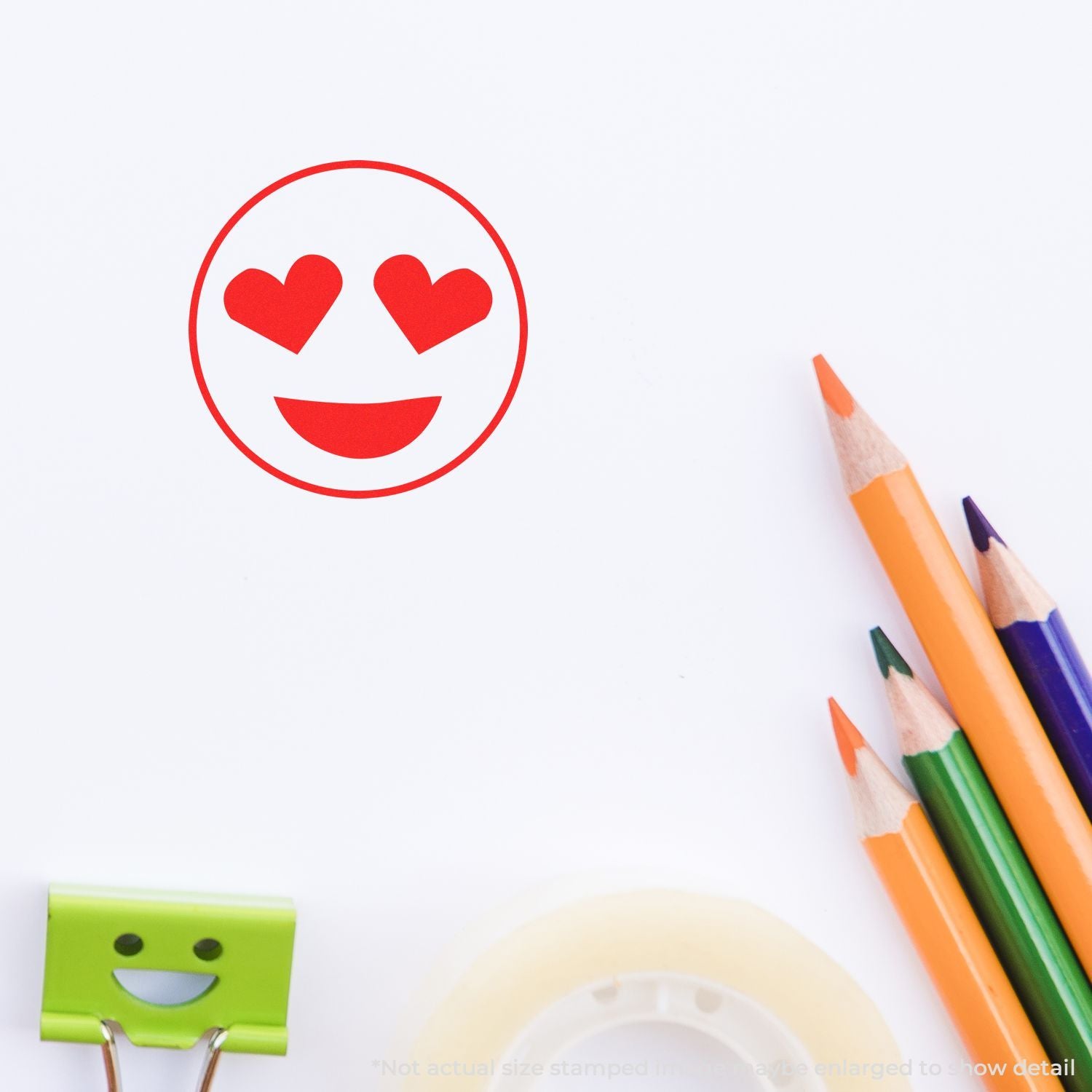 Heart eyes emoji stamp on white paper with colorful pencils, cute stationery and creative school supplies.