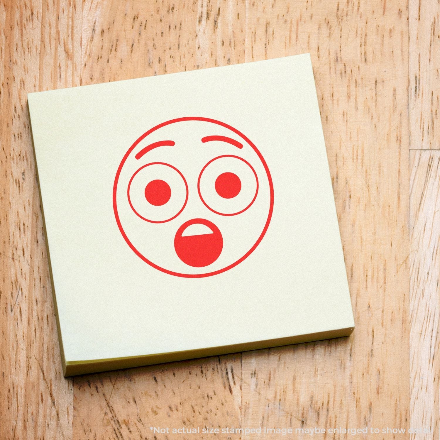 Sticky note with red shocked face emoji icon on a wooden background