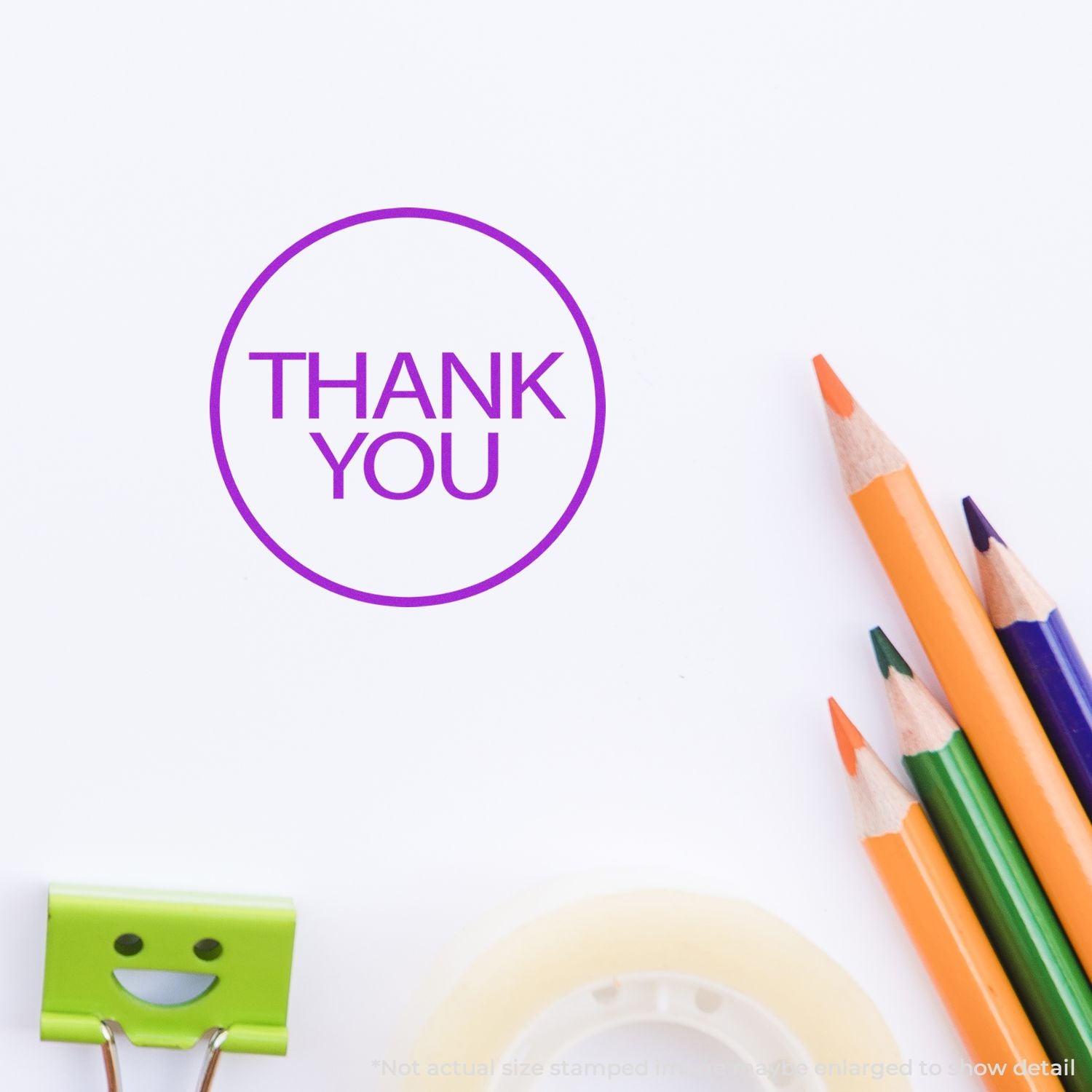 Thank you stamp on white paper with colorful pencils and stationery items on a clean background.