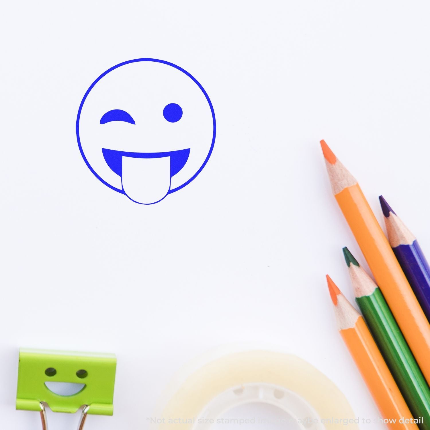 Winking smiley face stamp with tongue out next to colorful pencils on white background, cute stationery concept