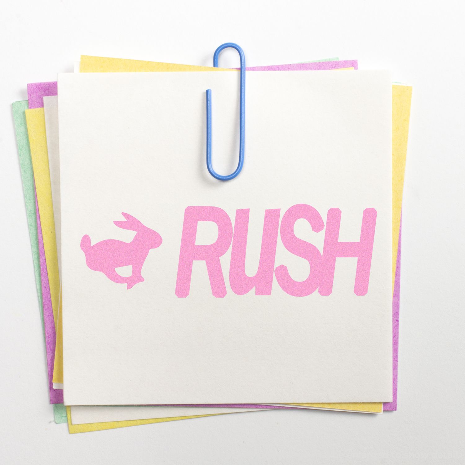 Urgent RUSH stationery with pink logo text and paperclip on stacked colored note cards for expedited service messaging