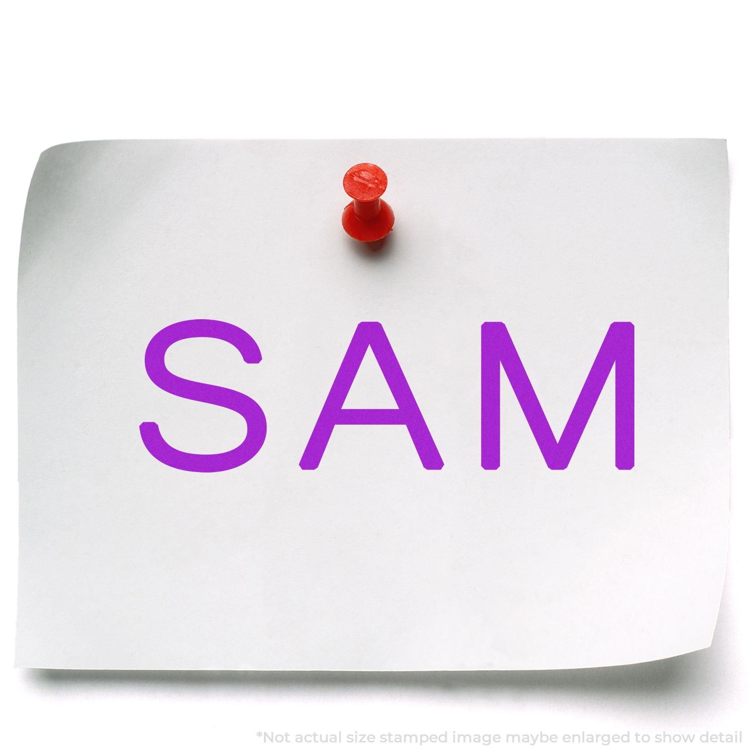 Pinned SAM stamp on white paper with purple letters, showing custom stamping or labeling for mail, forms, or crafts.