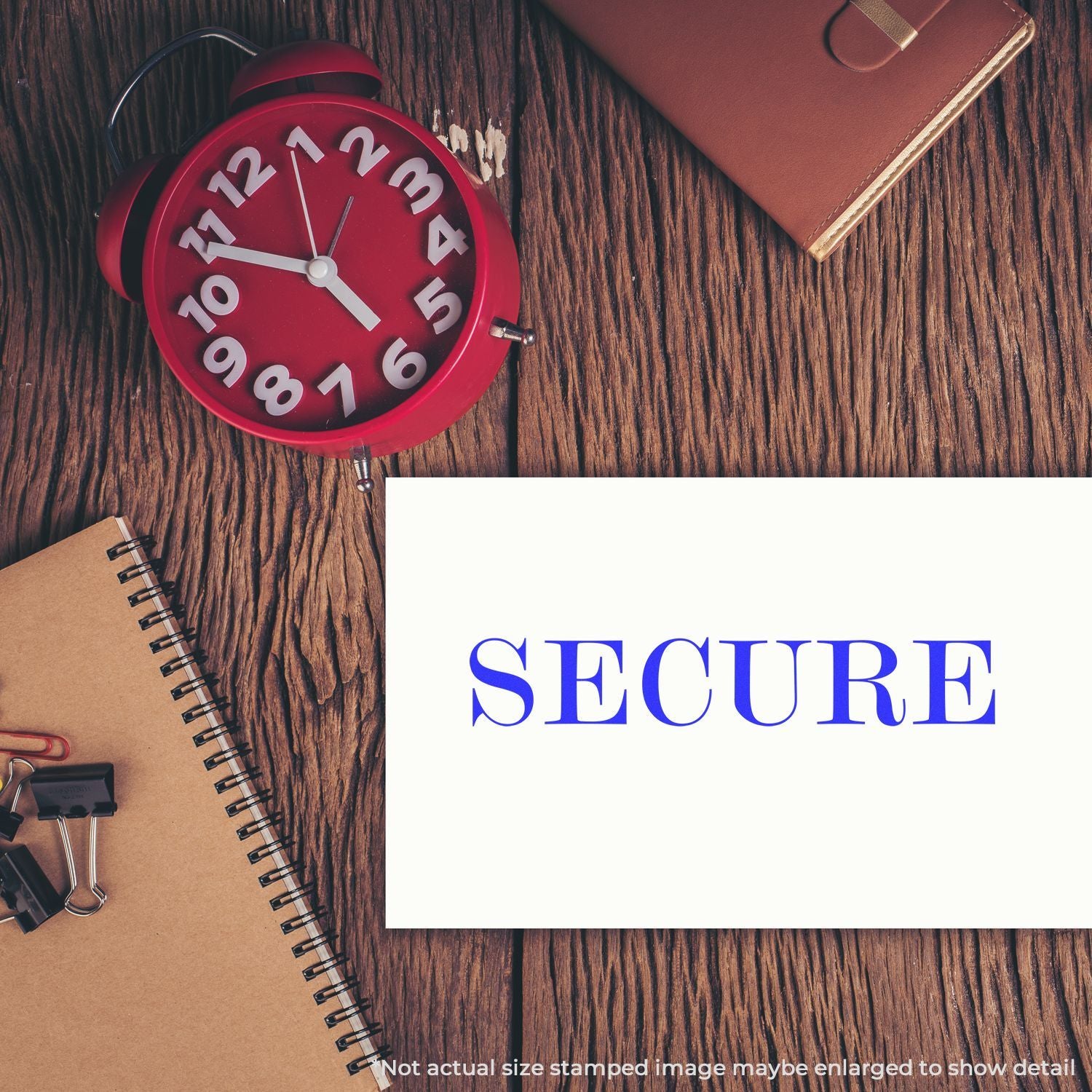 Red alarm clock and stationery beside a SECURE document stamp on a wooden desk.