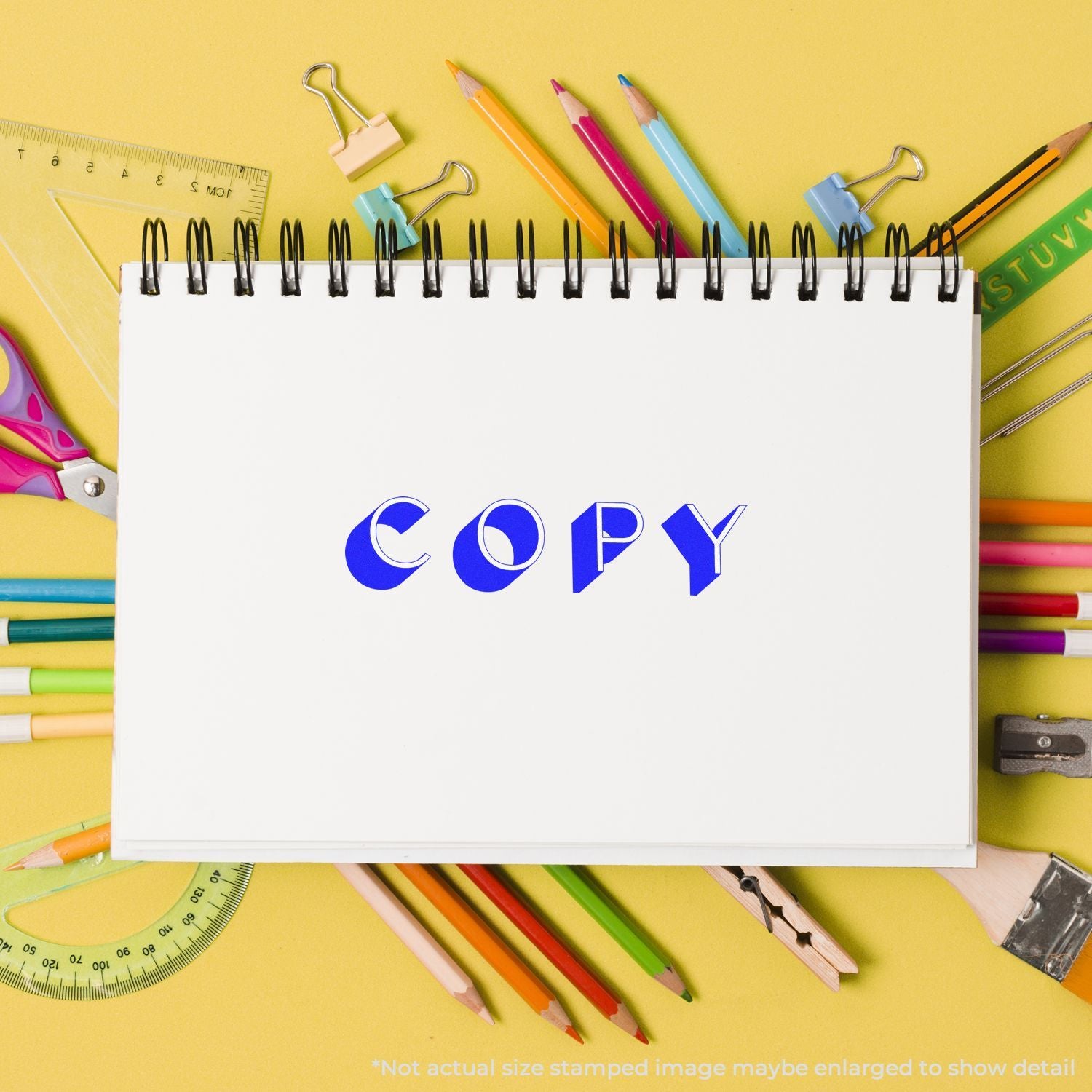 Blank spiral notebook with copy text surrounded by colorful school stationery on a yellow background, creative office supply flat lay.