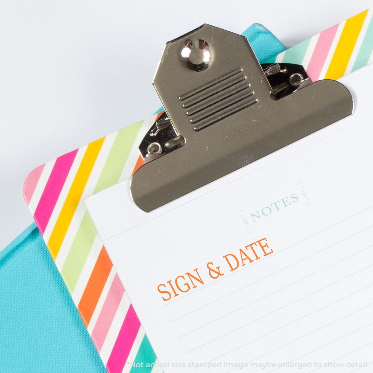 Colorful clipboard with striped notepad and Sign & Date form on a blue fabric background, close-up office stationery scene