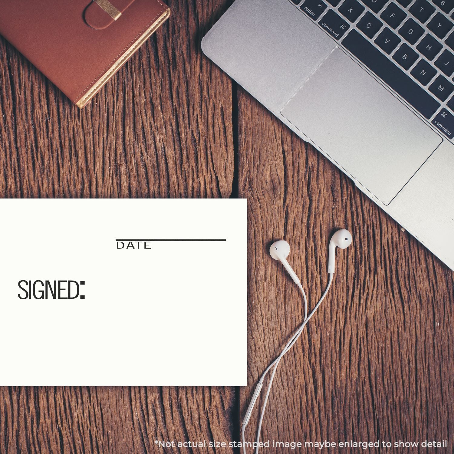 Flat lay of laptop, signed document, notebook, and earbuds on rustic wood desk, modern office workspace concept