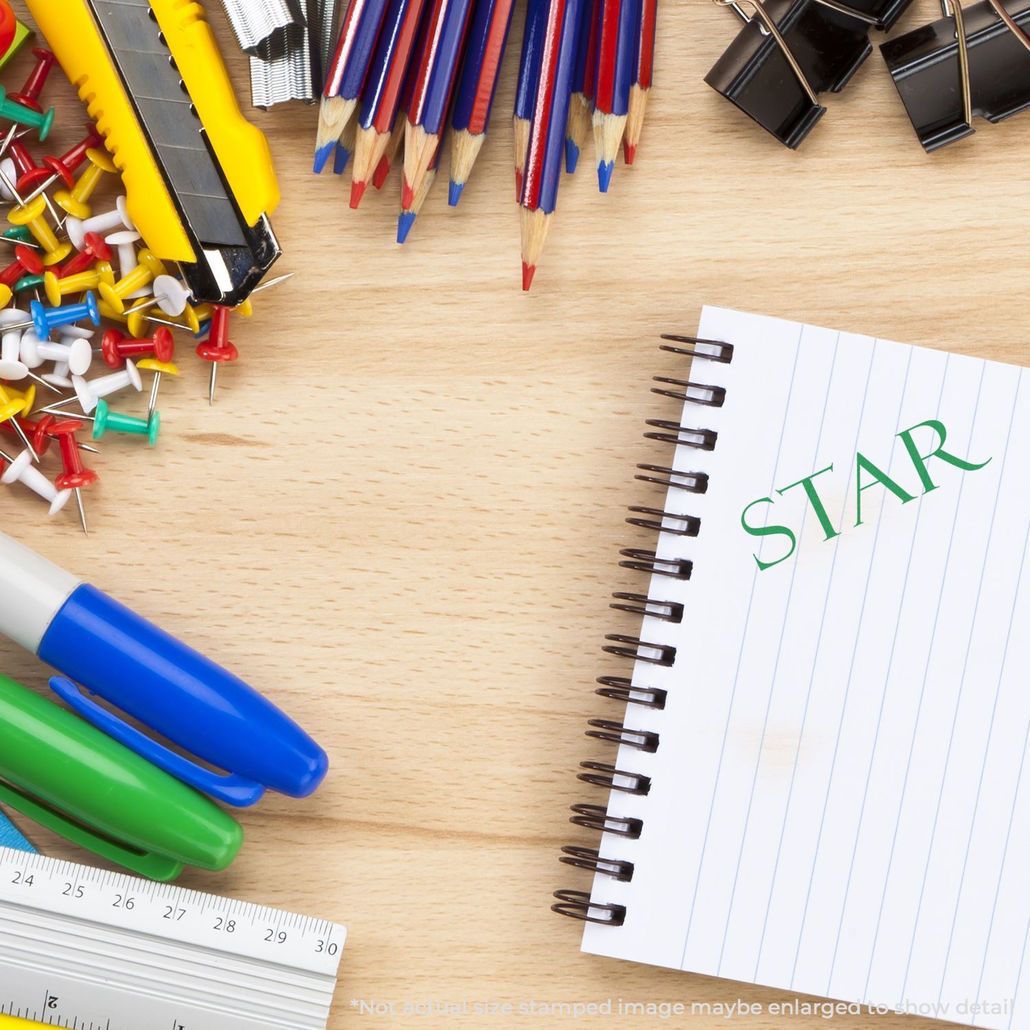 School stationery and office supplies on a wooden desk with notebook labeled STAR, pencils, pens, binder clips, push pins, and rulers.