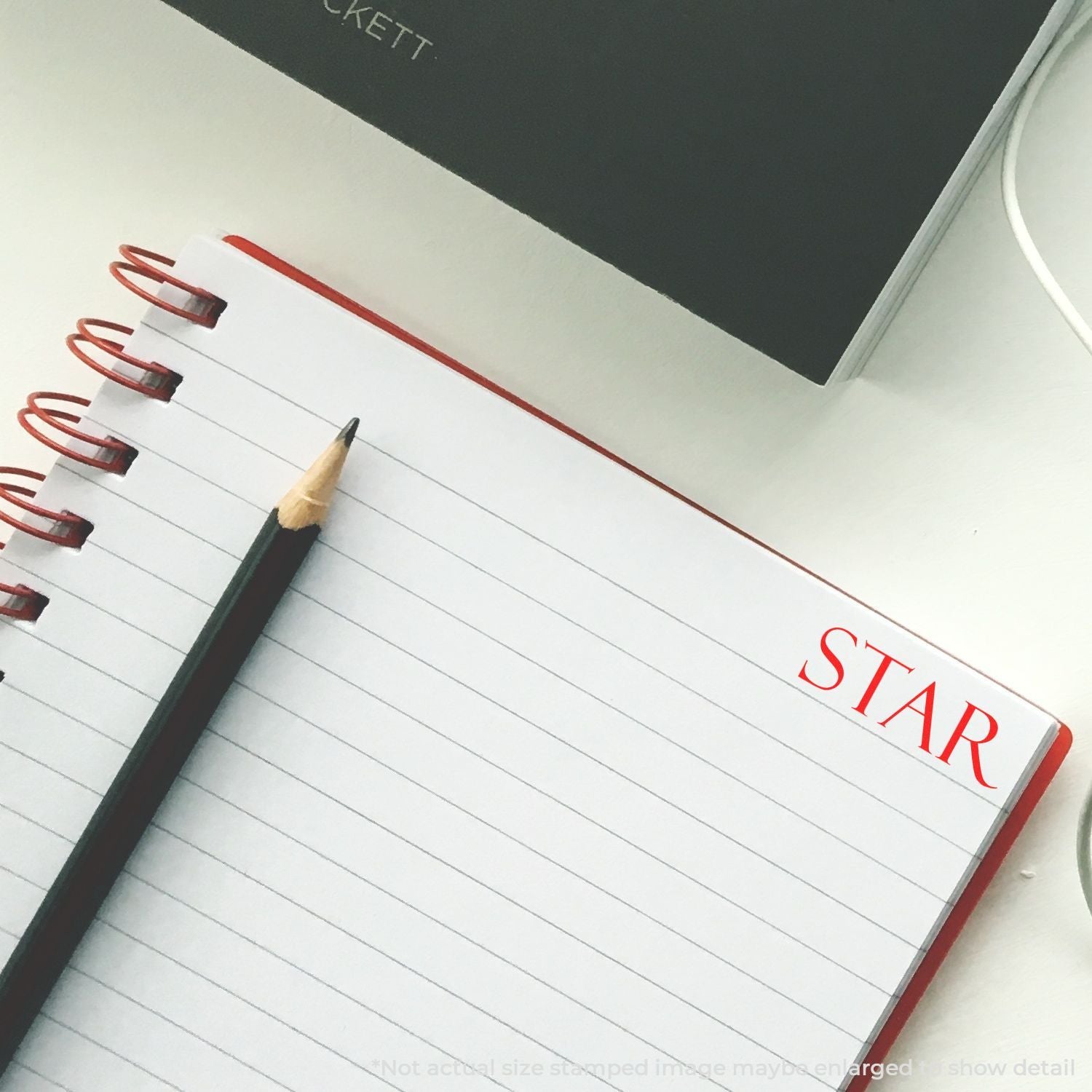 Lined spiral notebook with pencil and red trim on a clean white desk, ideal for school notes and stationery use.