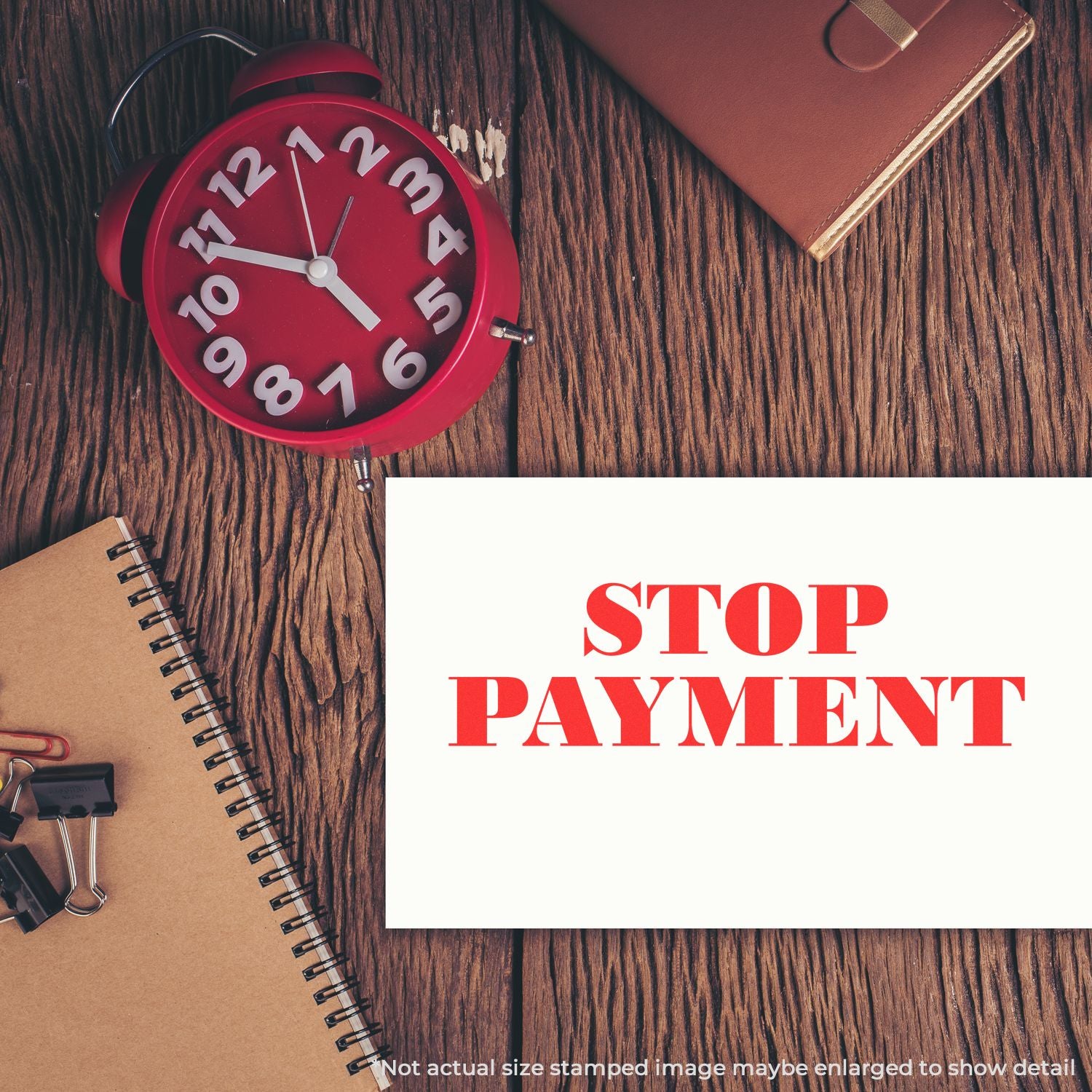 Red alarm clock and office desk with STOP PAYMENT message on a wooden background, illustrating canceled payment or financial deadline concept.