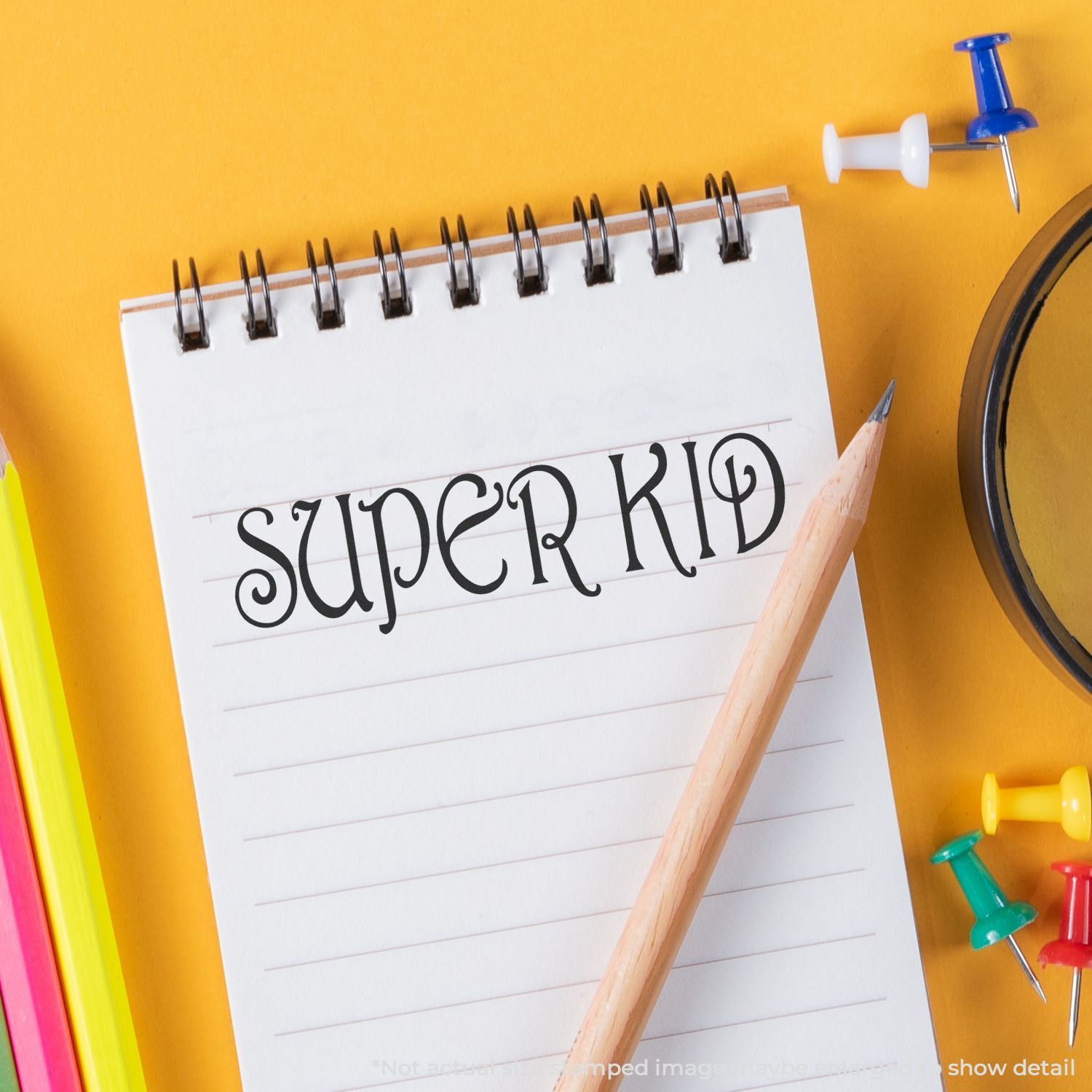 Super Kid notebook on yellow background with pencil and colorful push pins