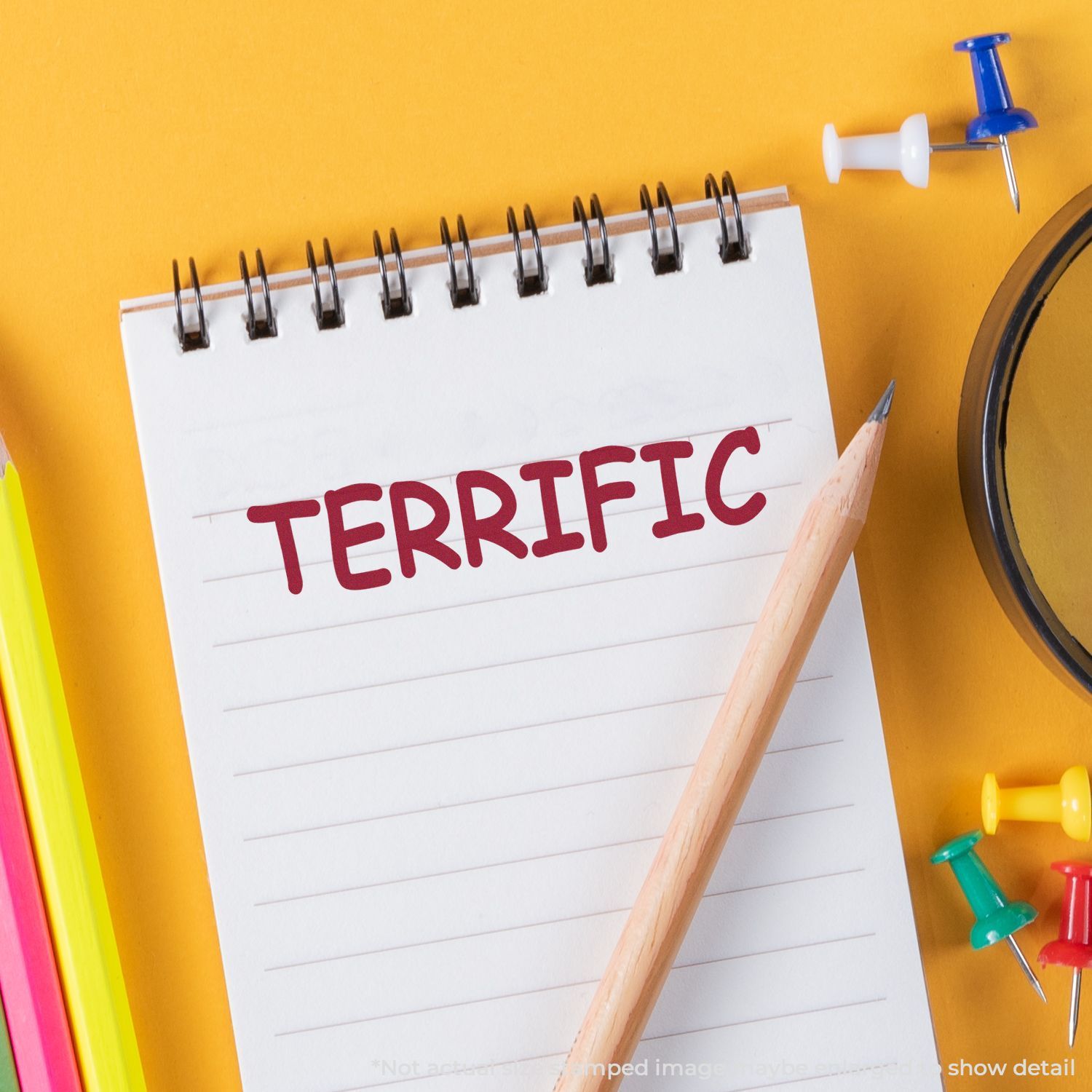 Terrific notebook page with pencil and colorful push pins on a yellow background