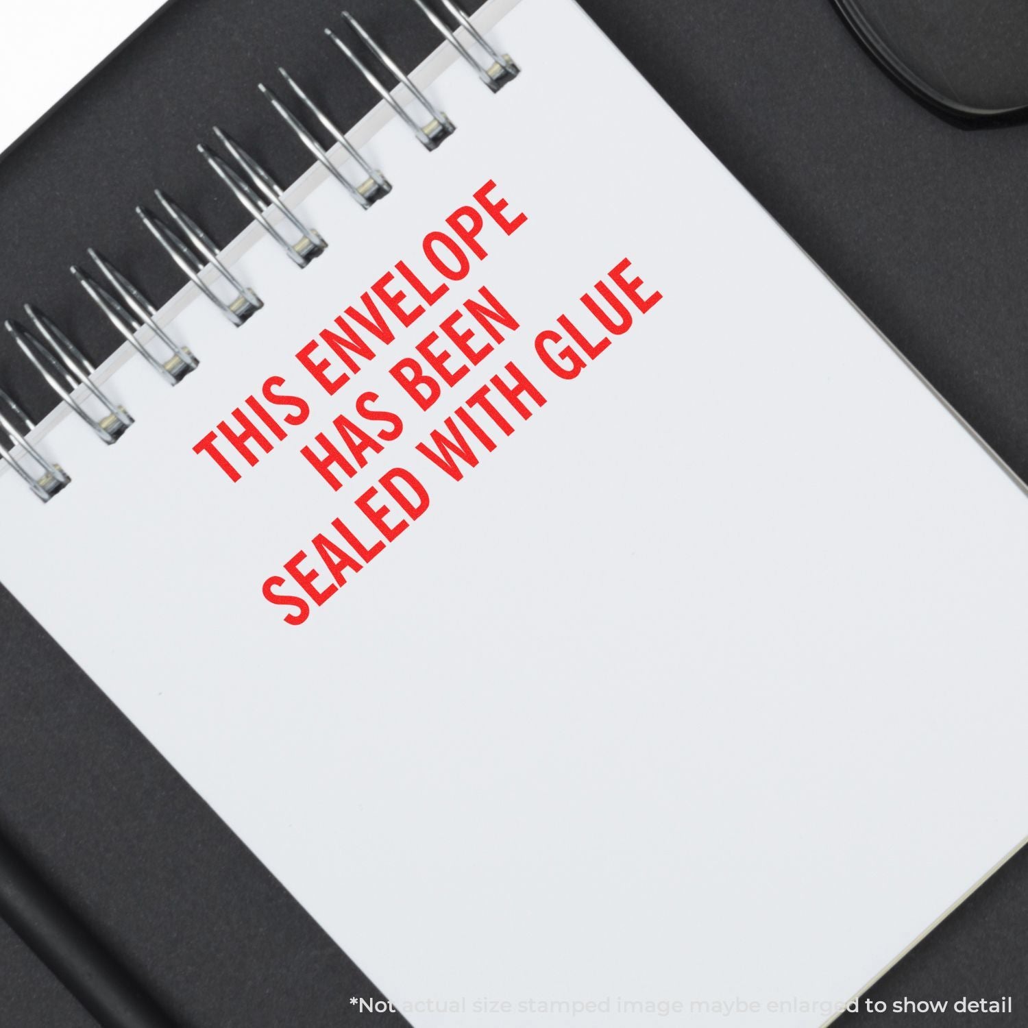 Spiral notebook with red text reading This envelope has been sealed with glue on a white page.