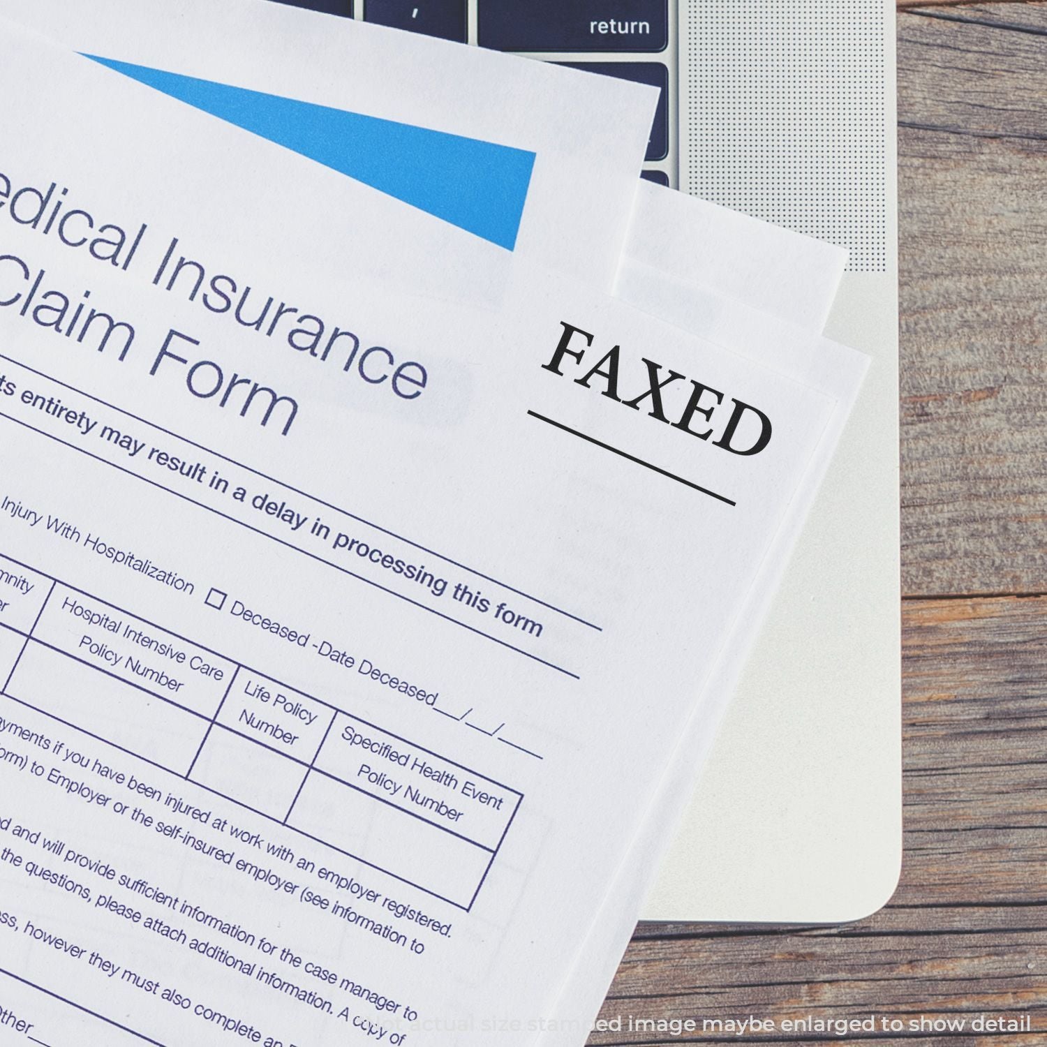 Faxed medical insurance claim form on laptop with paperwork on wooden desk.