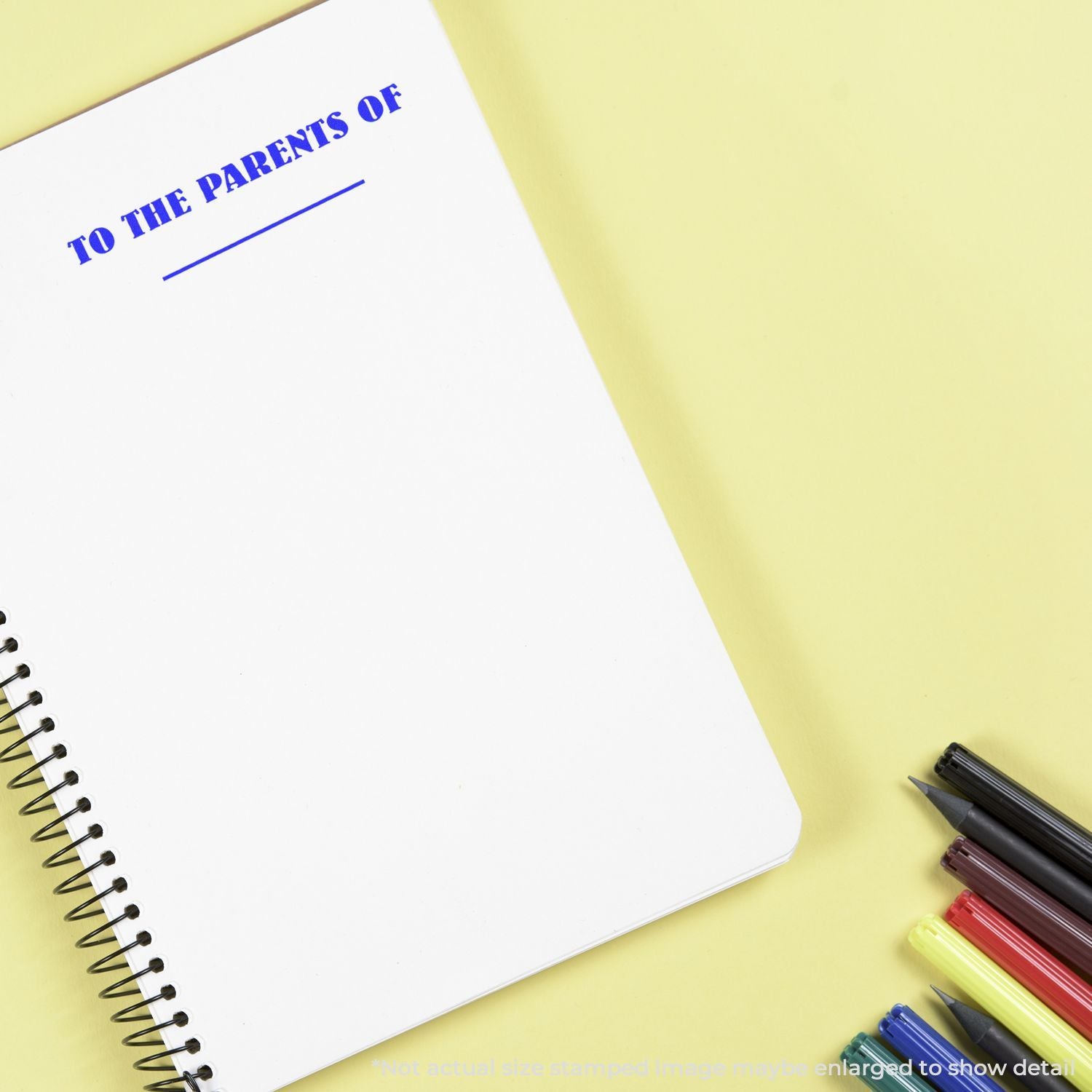Blank spiral notebook page titled To the Parents Of with colorful markers on a yellow background.