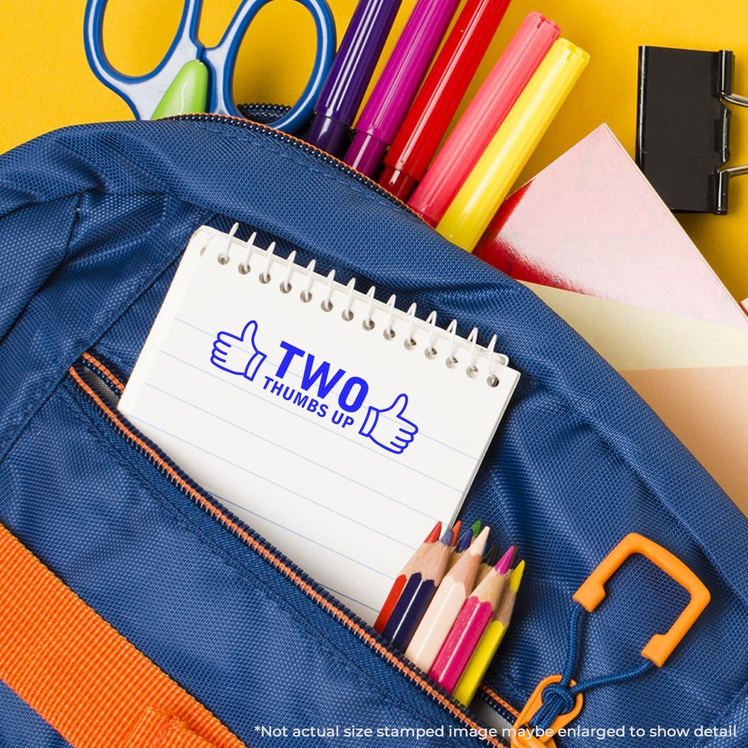 Back-to-school supplies: blue pencil pouch with notebook Two Thumbs Up, crayons, markers, and scissors for learning.