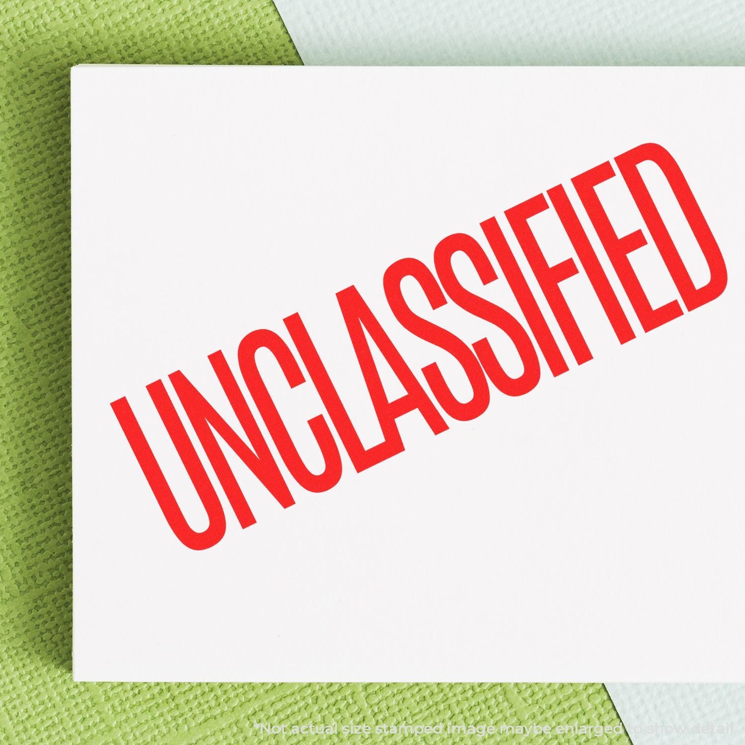 Red unclassified stamp on white paper over green background, security document classified label close-up