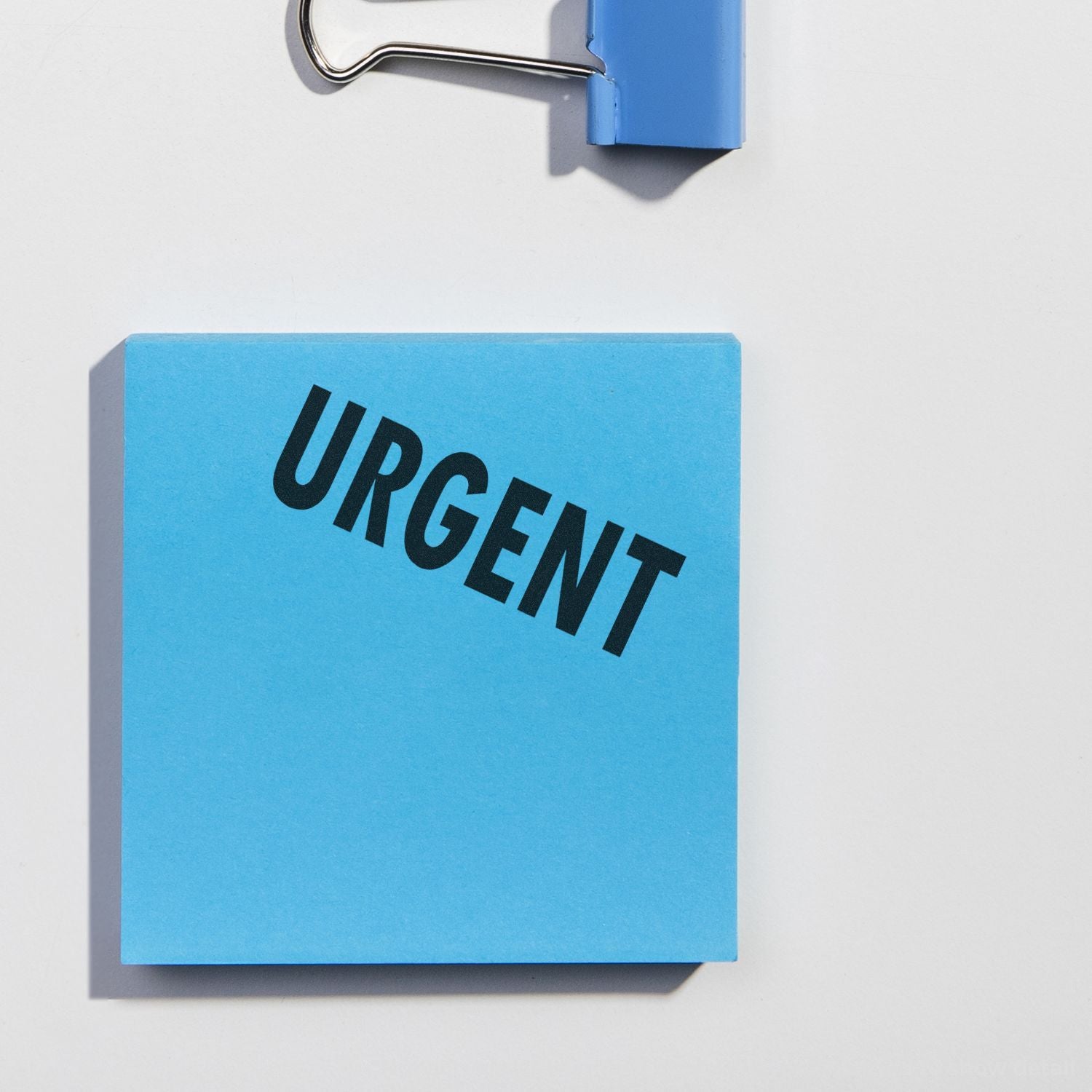 Close-up of a blue paper sign reading URGENT, highlighting time-sensitive priority and urgent notification context.