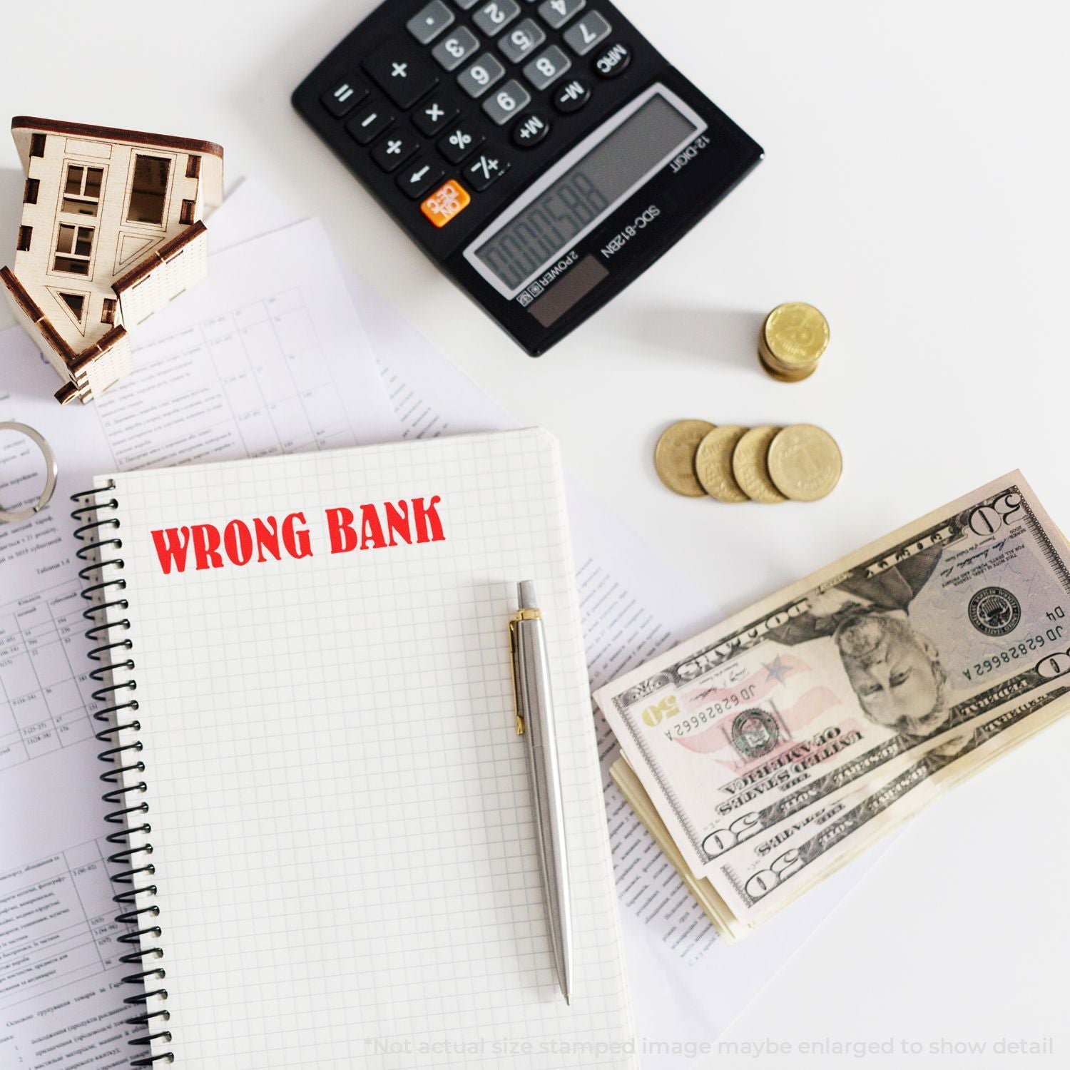 Wrong bank mortgage and finance concept with calculator, house model, cash, coins, and notebook on a white desk.