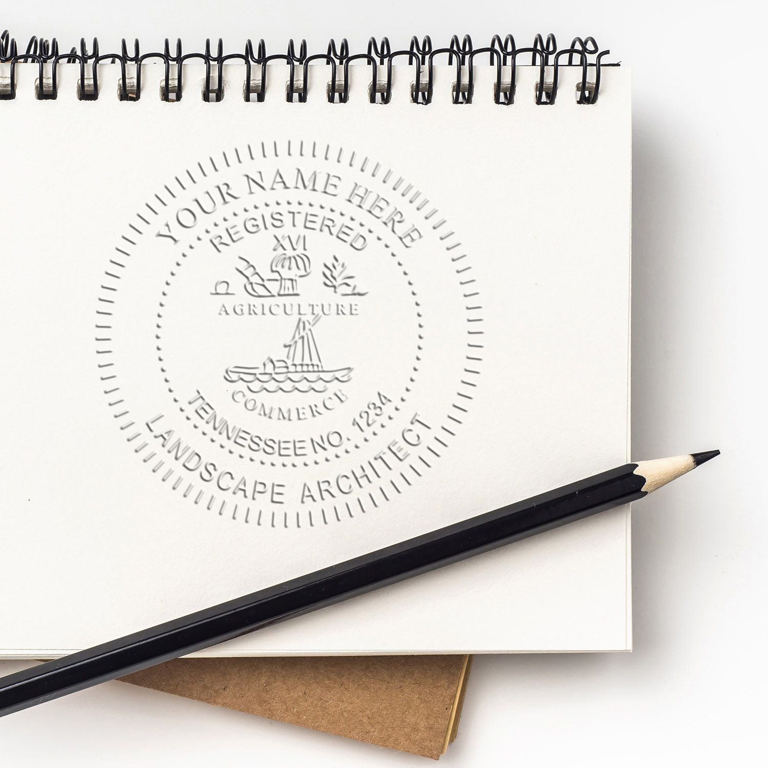 Embossed landscape architecture logo on a spiral sketchbook with pencil, featuring a Tennessee registered seal design.