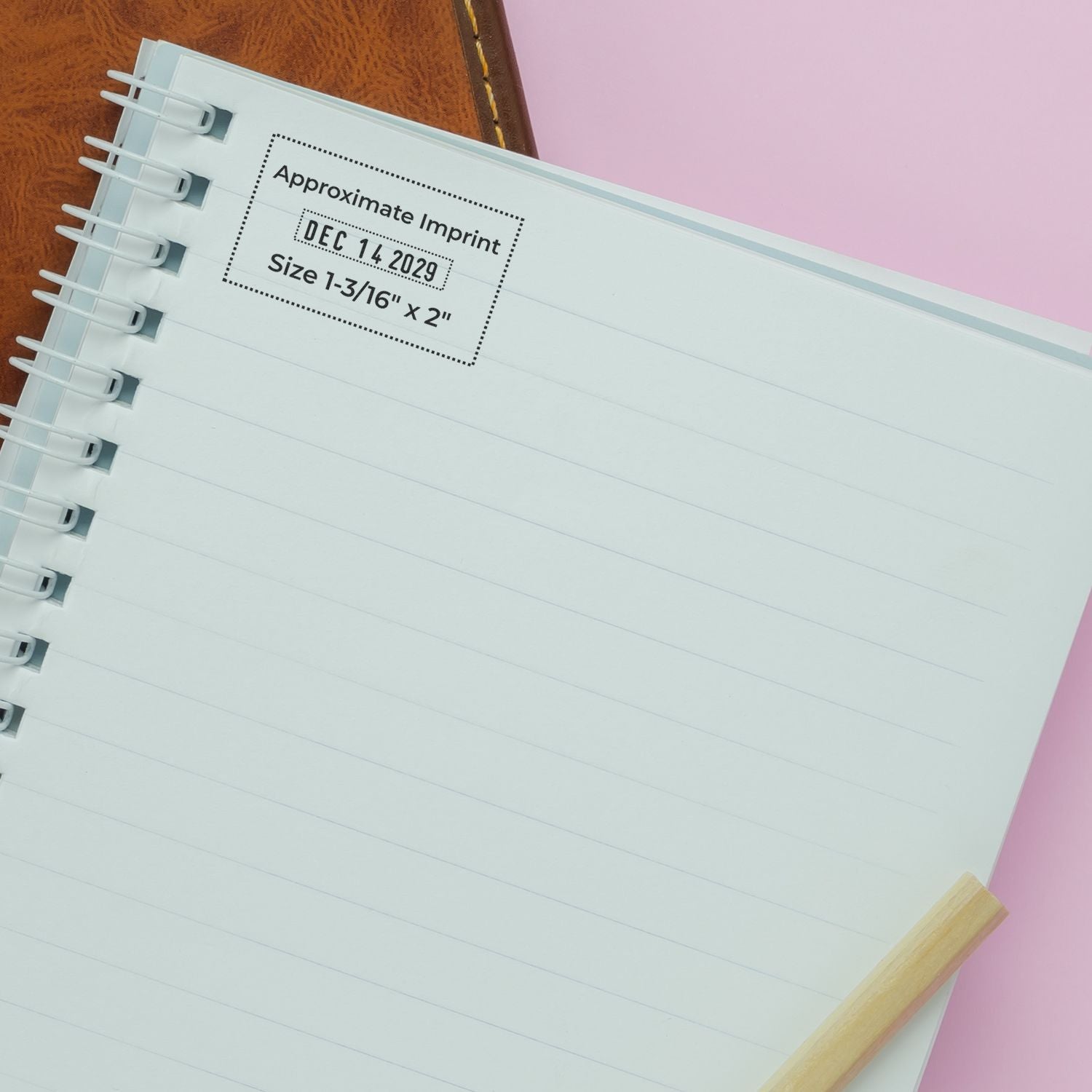 Blank spiral notebook page with approximate imprint date and size details, shown on a pink background with a pencil.