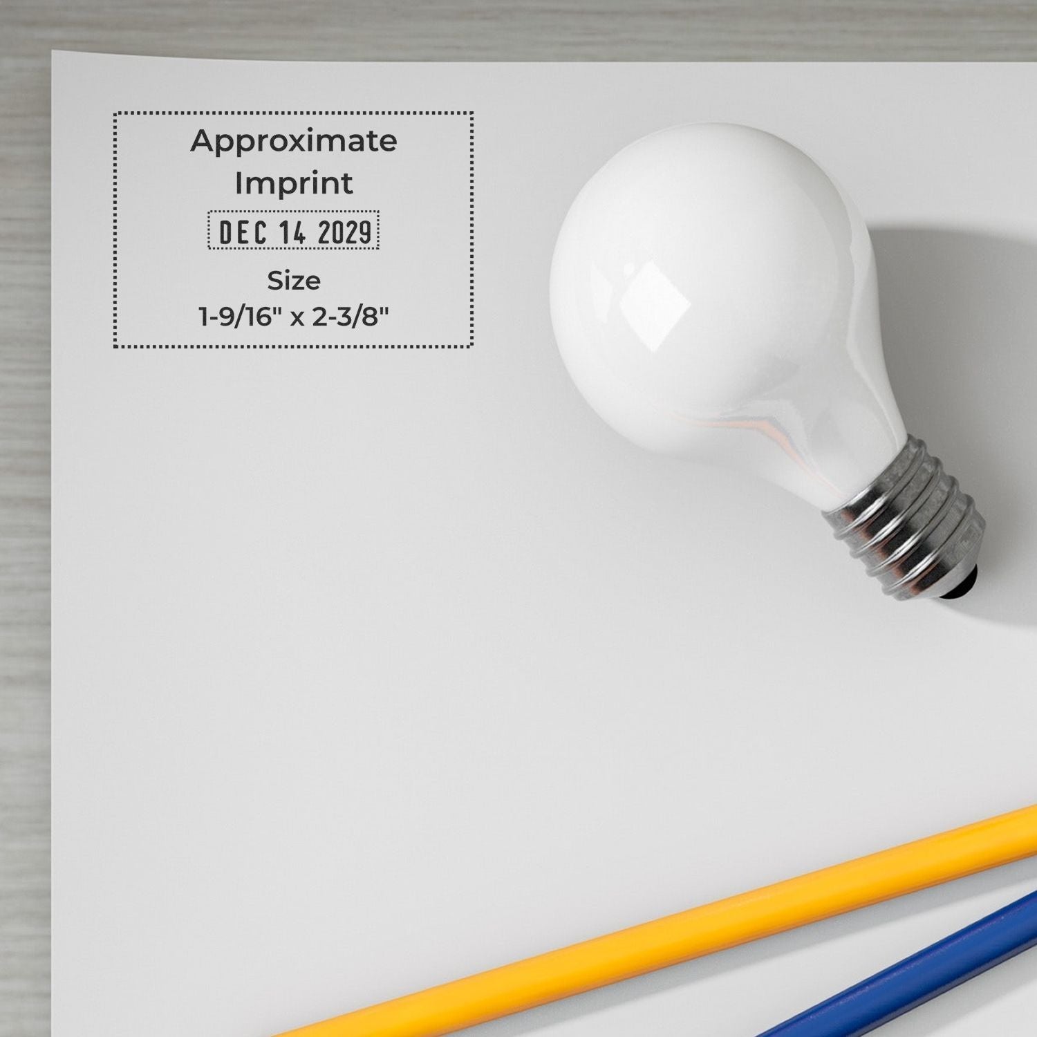 Light bulb mockup with approximate imprint area, date Dec 14 2029, size 1-9/16" x 2-3/8", on white background with pencils.