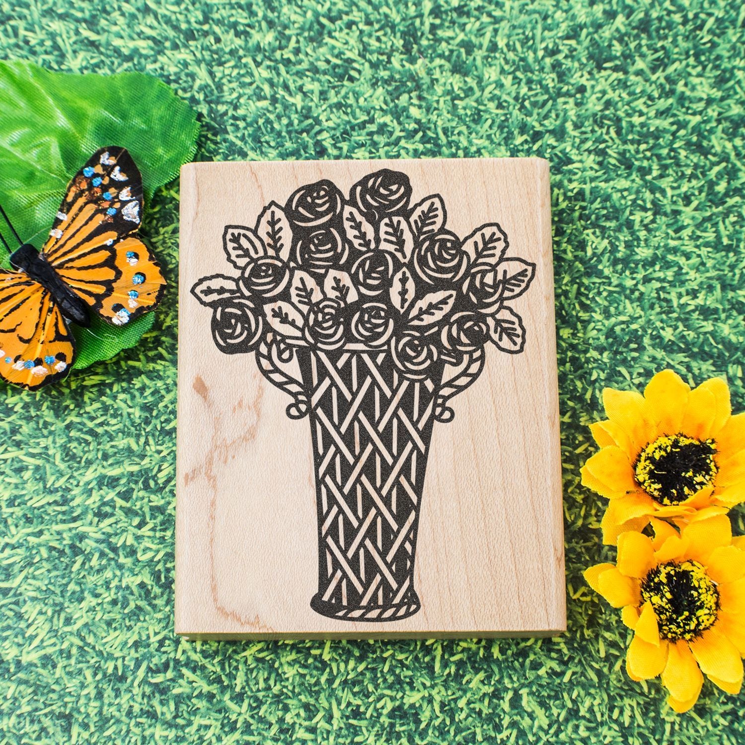 Wooden floral bouquet stamp with butterfly and sunflower on grass background