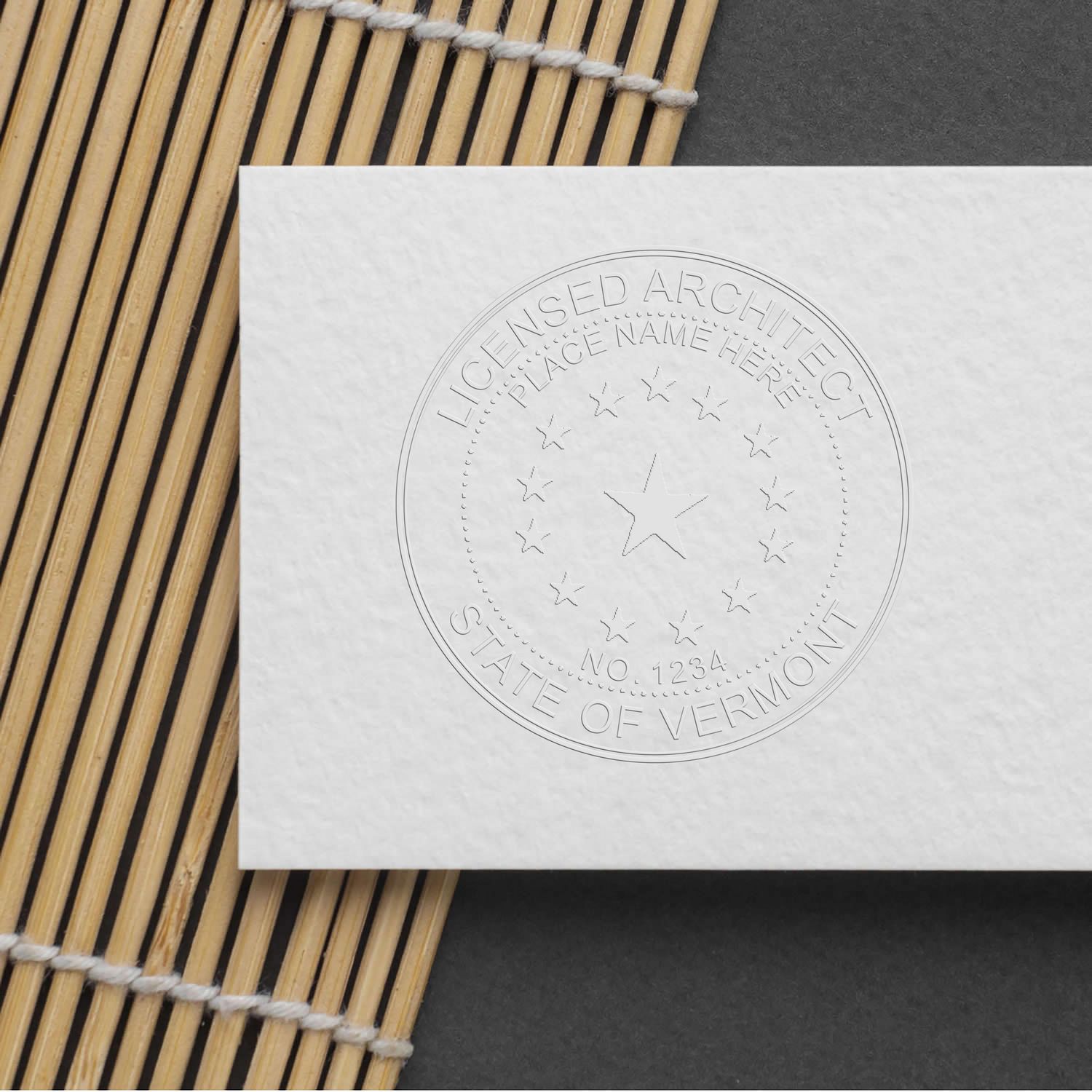 Embossed Licensed Architect State of Vermont seal on white paper with bamboo mat background.