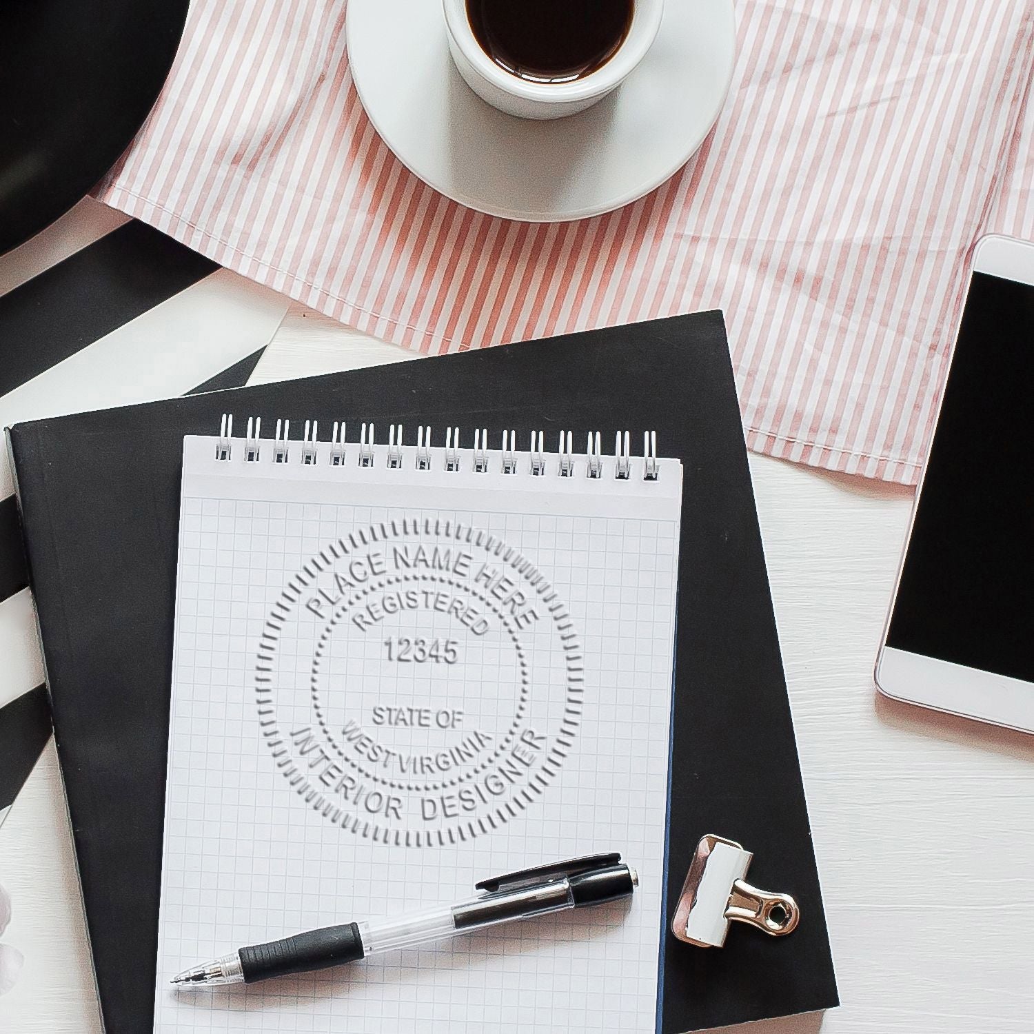 Interior designer desk flat lay with notebook, pen, coffee cup, and smartphone, featuring a West Virginia interior designer stamp mockup.