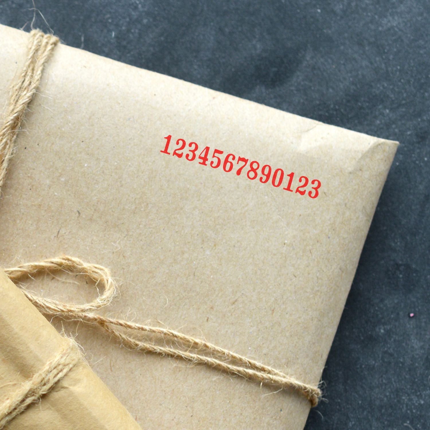 Kraft paper gift package wrapped with twine and red barcode numbers on dark background