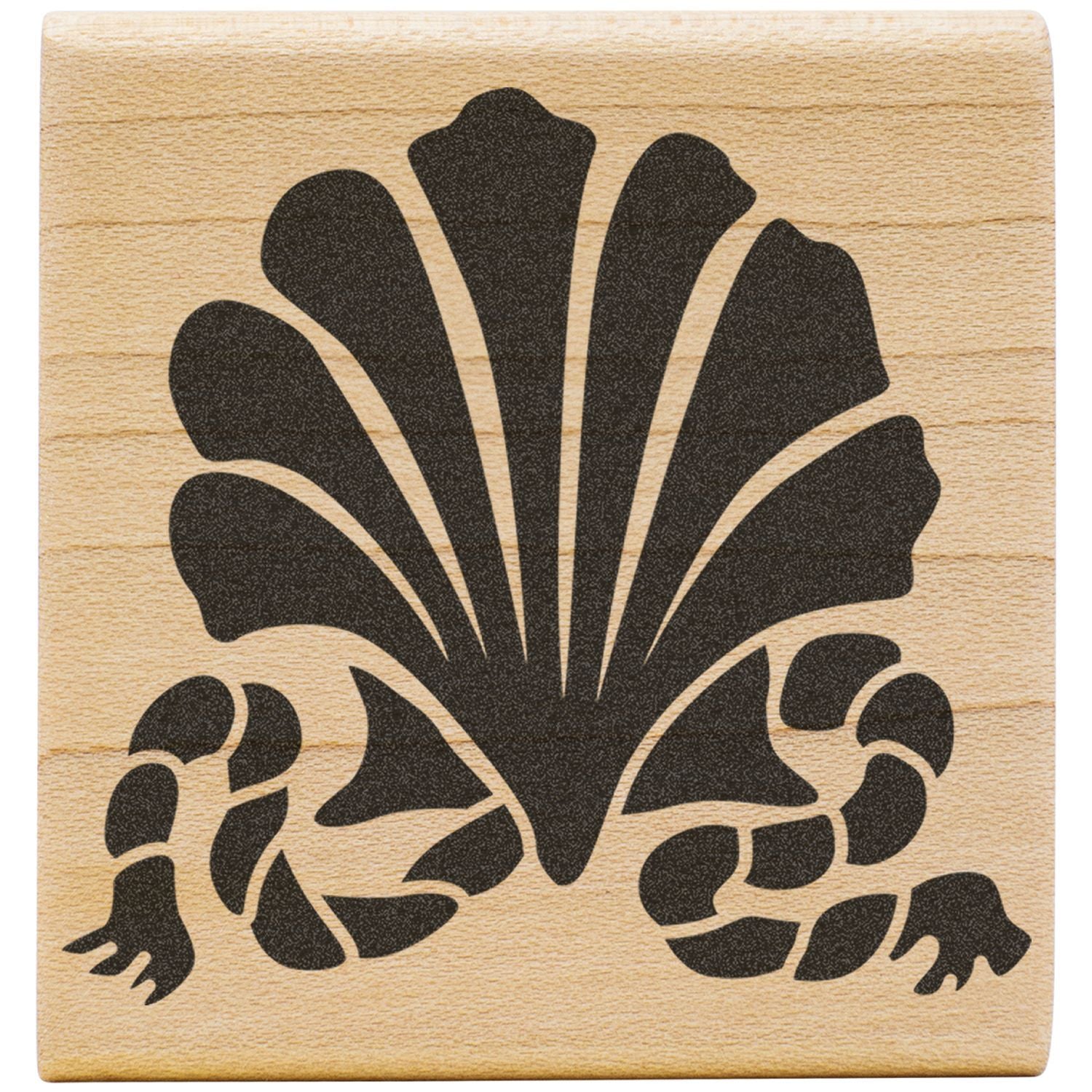 Black floral shell design on a wooden block stamp, decorative emblem pattern.