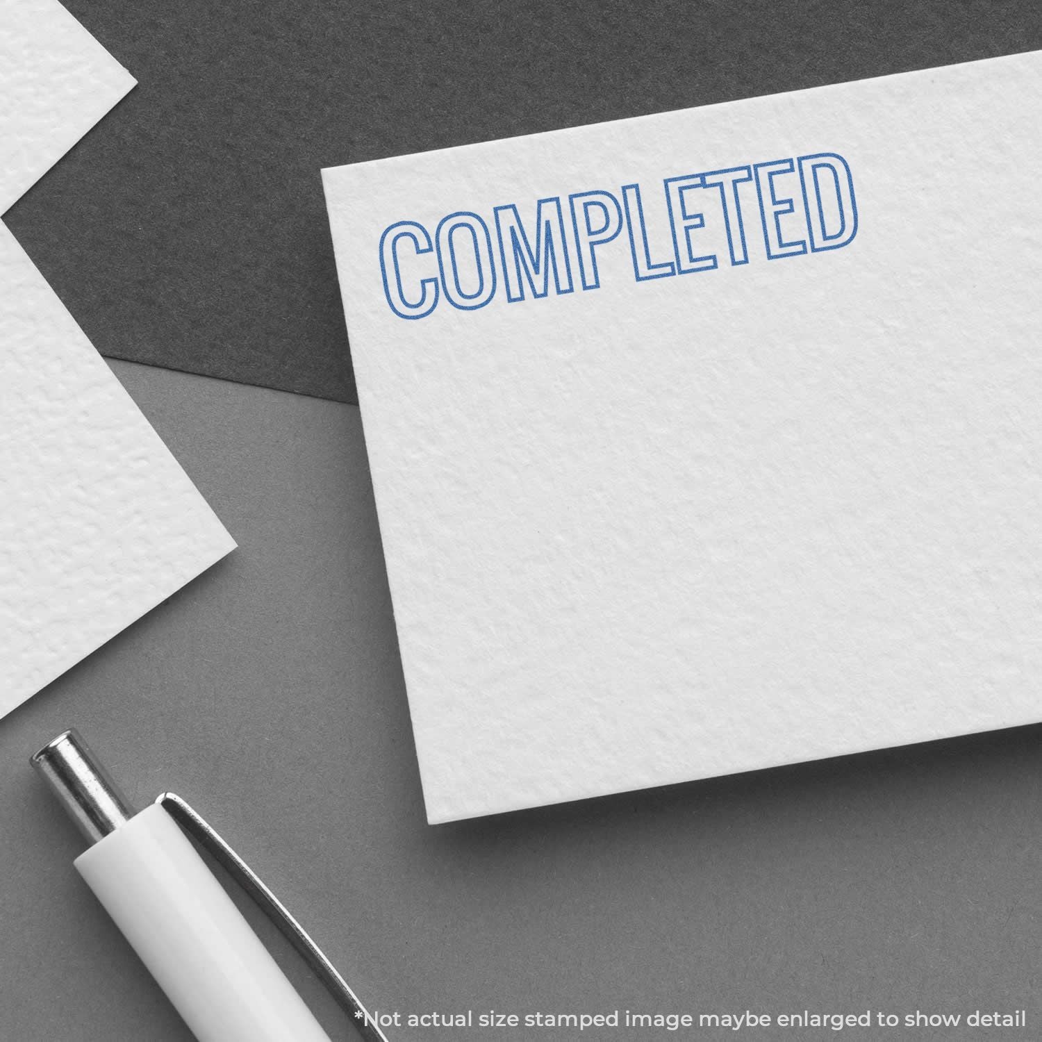 Completed stamp on a white note card with pen on a gray background, signaling task or project completion