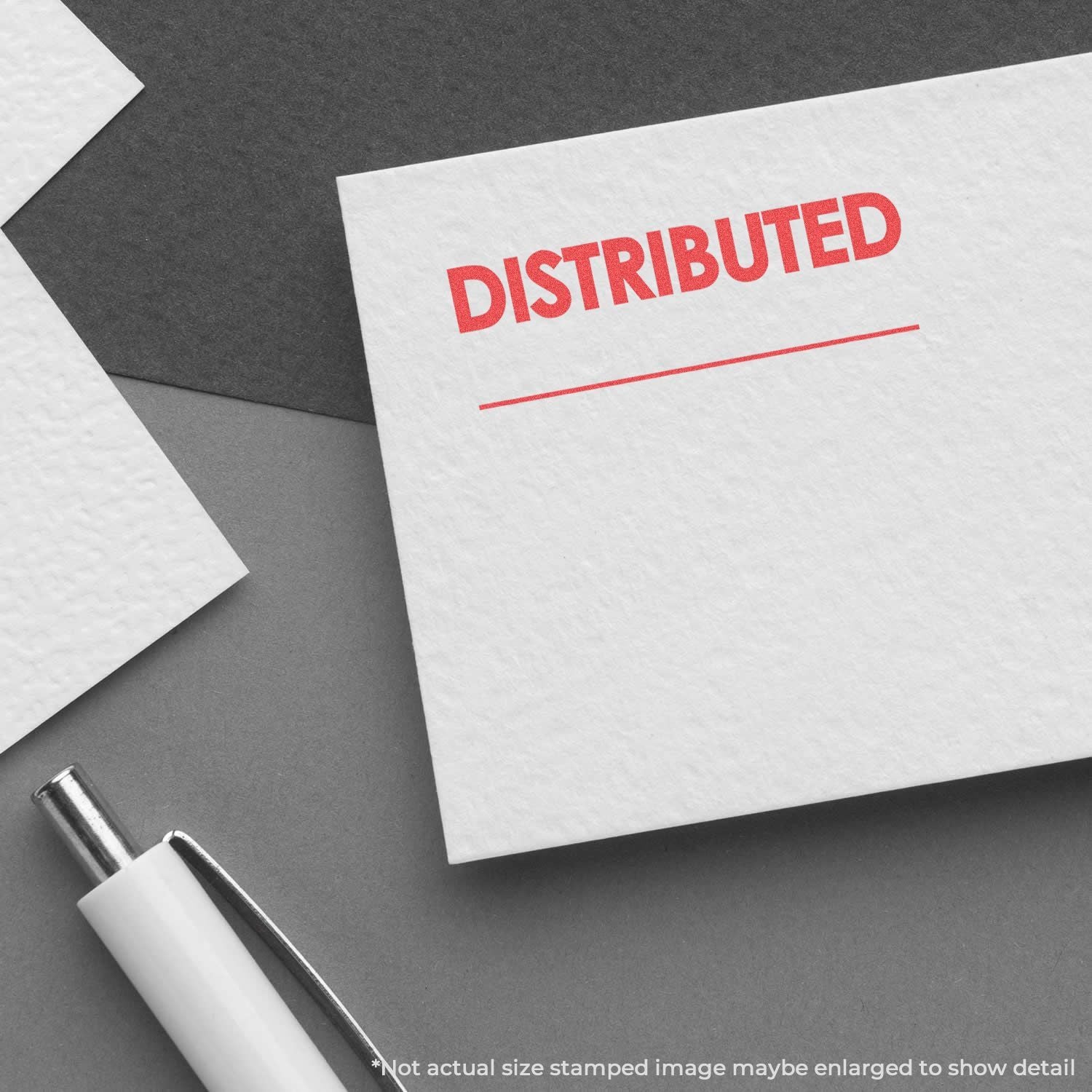 Document with red DISTRIBUTED stamp, symbolizing distributed materials and logistics paperwork with pen on gray background management.